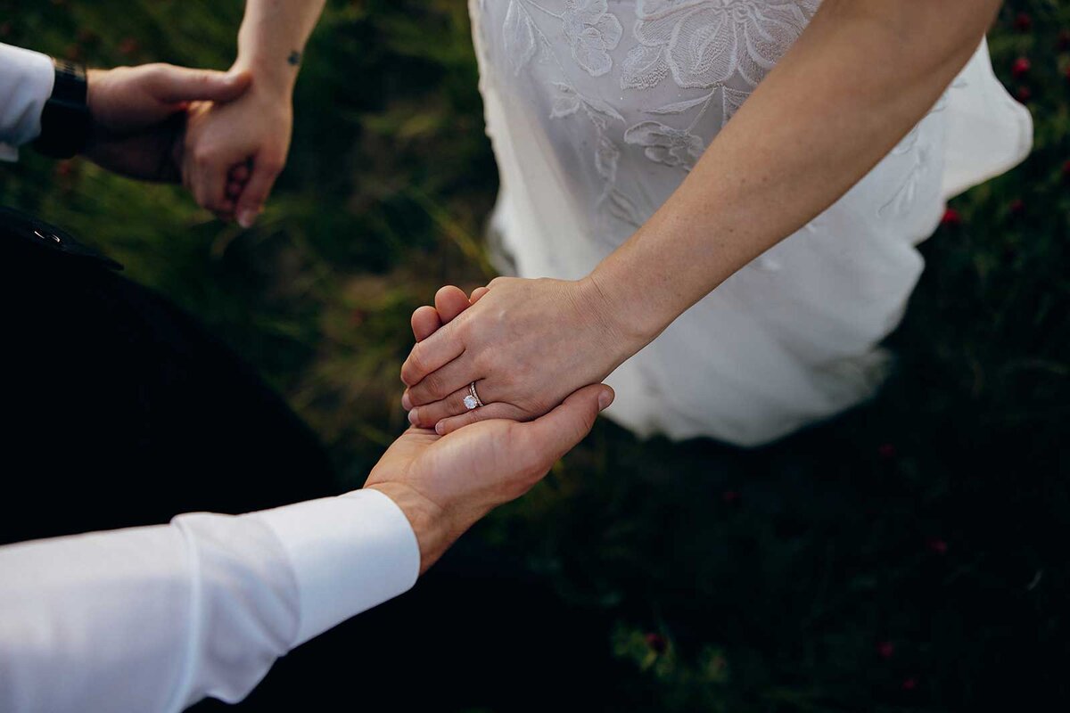 Two people holding hands standing in grass