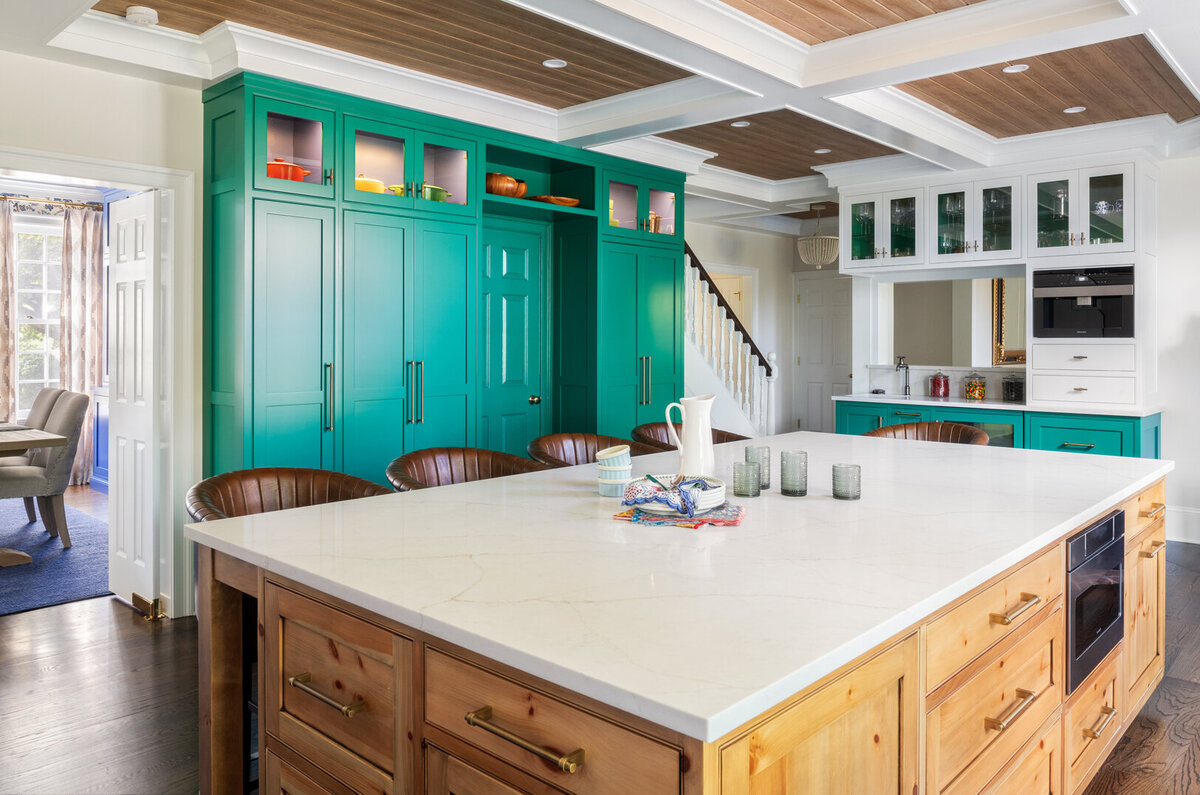 bright white kitchen with light wood accents, dark teal cabinets and a large wooden island