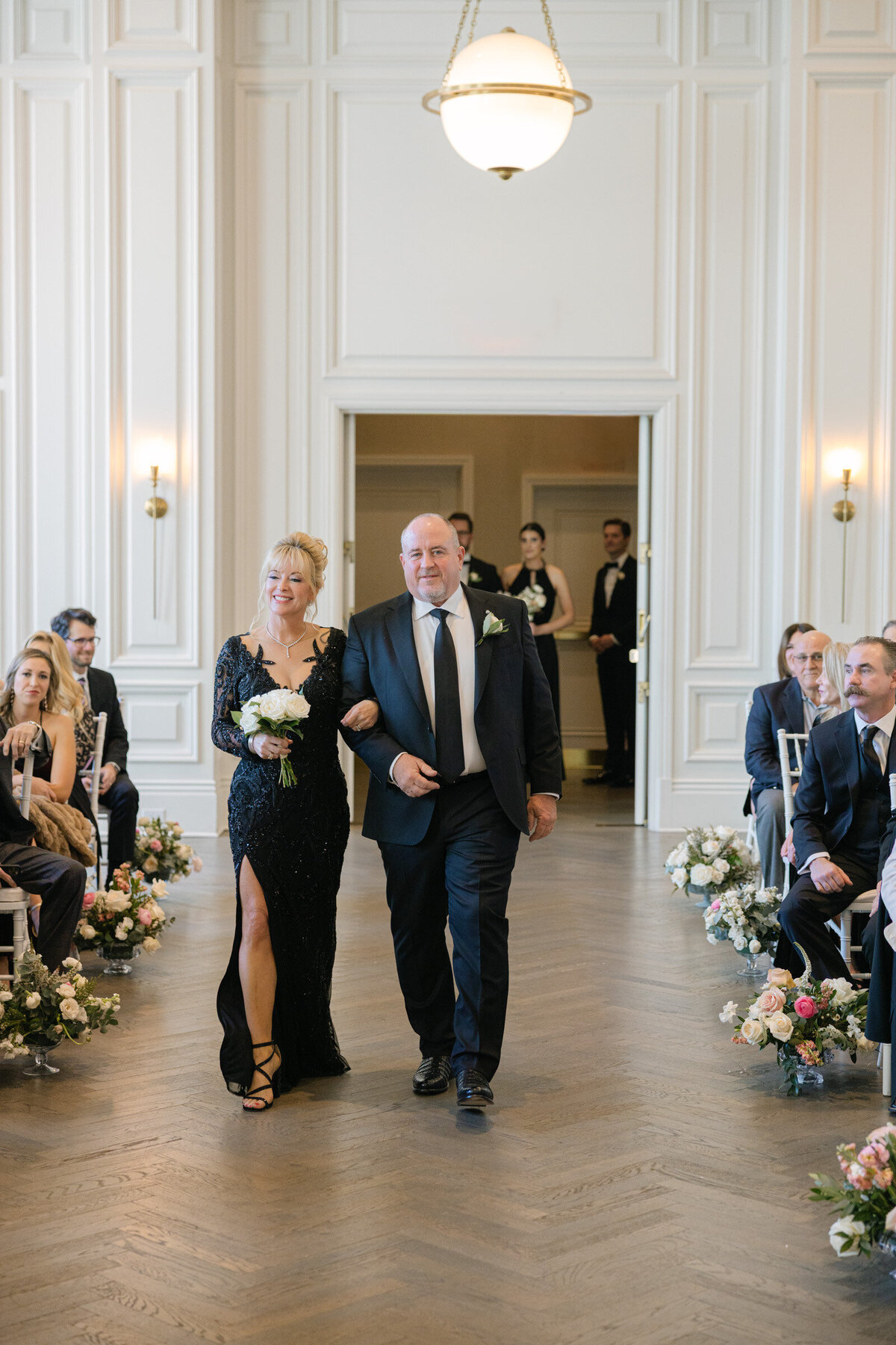 parents walking down the aisle as the wedding ceremony begins in the Governor’s Room at The Adolphus in Dallas, capturing a heartfelt and elegant moment.