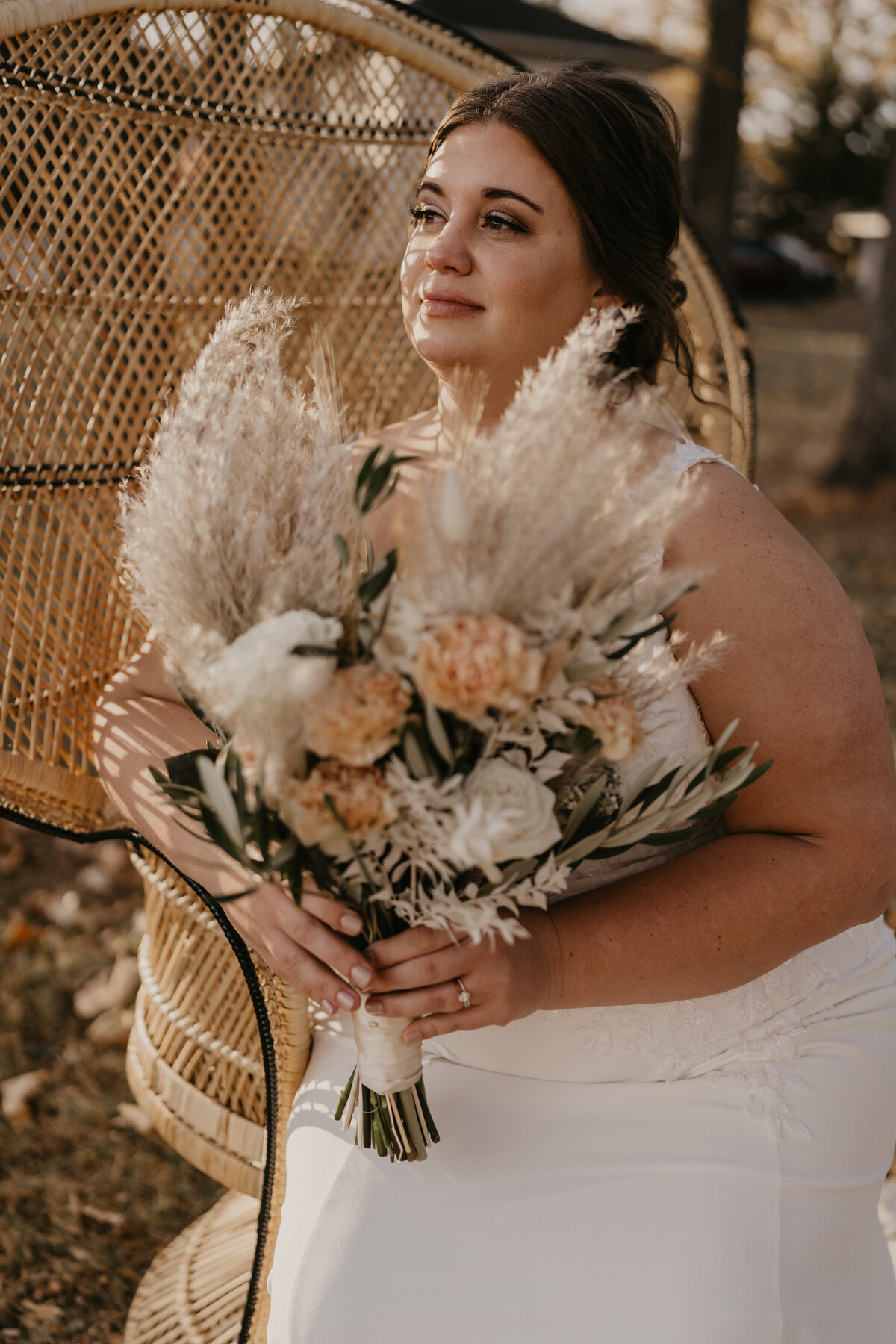 Bride's portrait with floral bouquet sitting on a vintage wicker chair.
