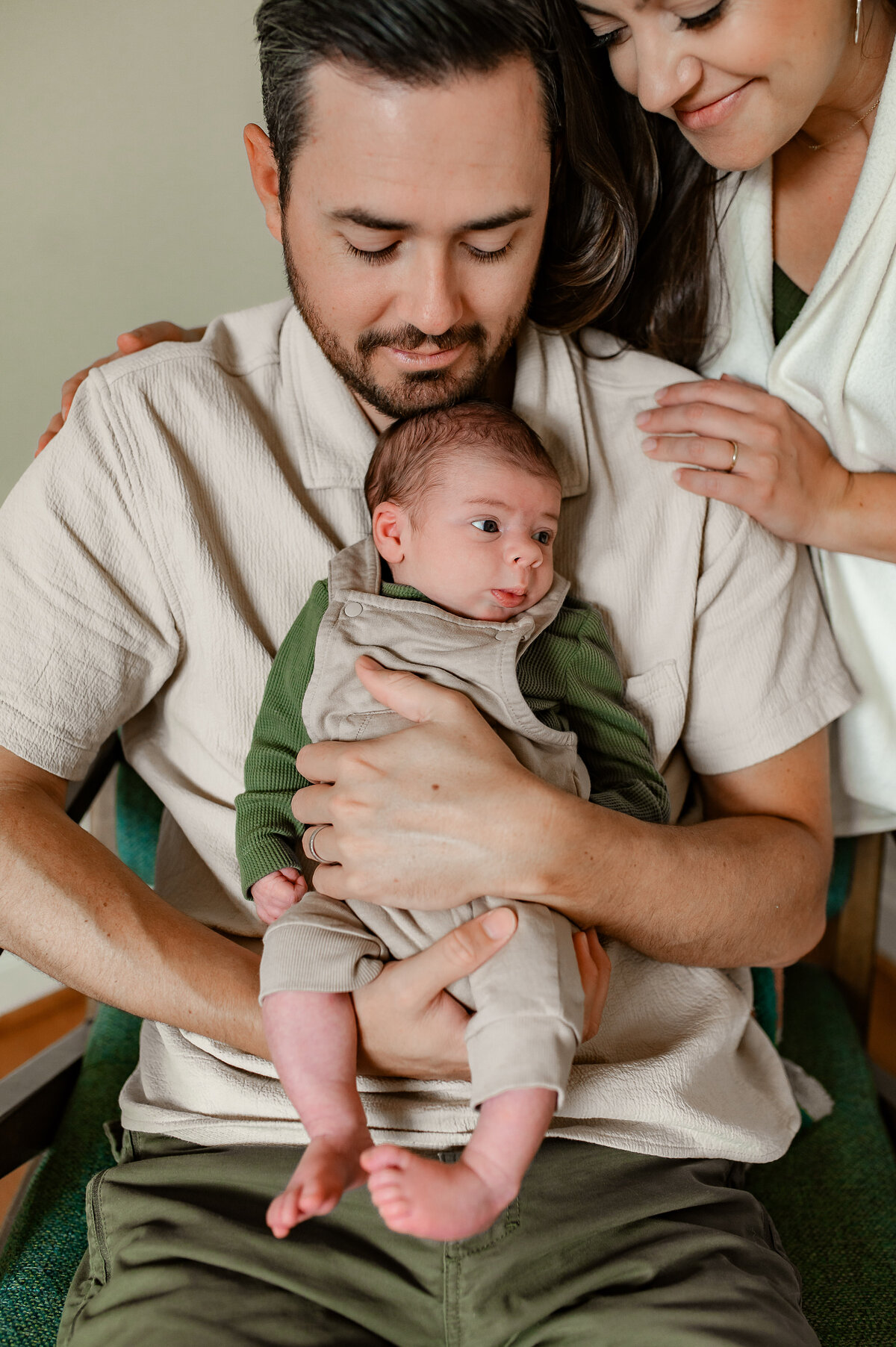 Mother and father cuddle baby by window in Ijamsville, MD