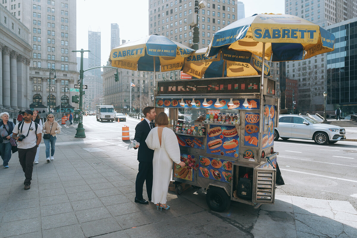 couple getting hot dogs after eloping at NY City Hall shot by Elsie Goodman Photography | NYC Elopement Packages