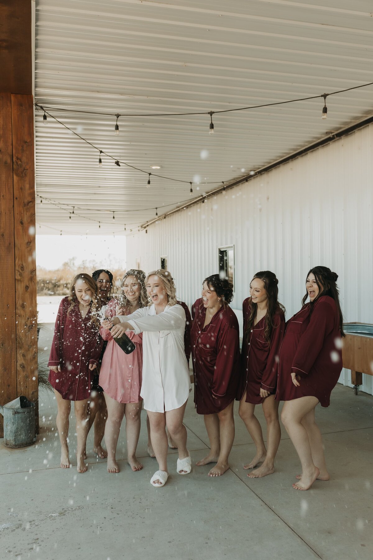 bride popping bubbly with bridal party in pjs