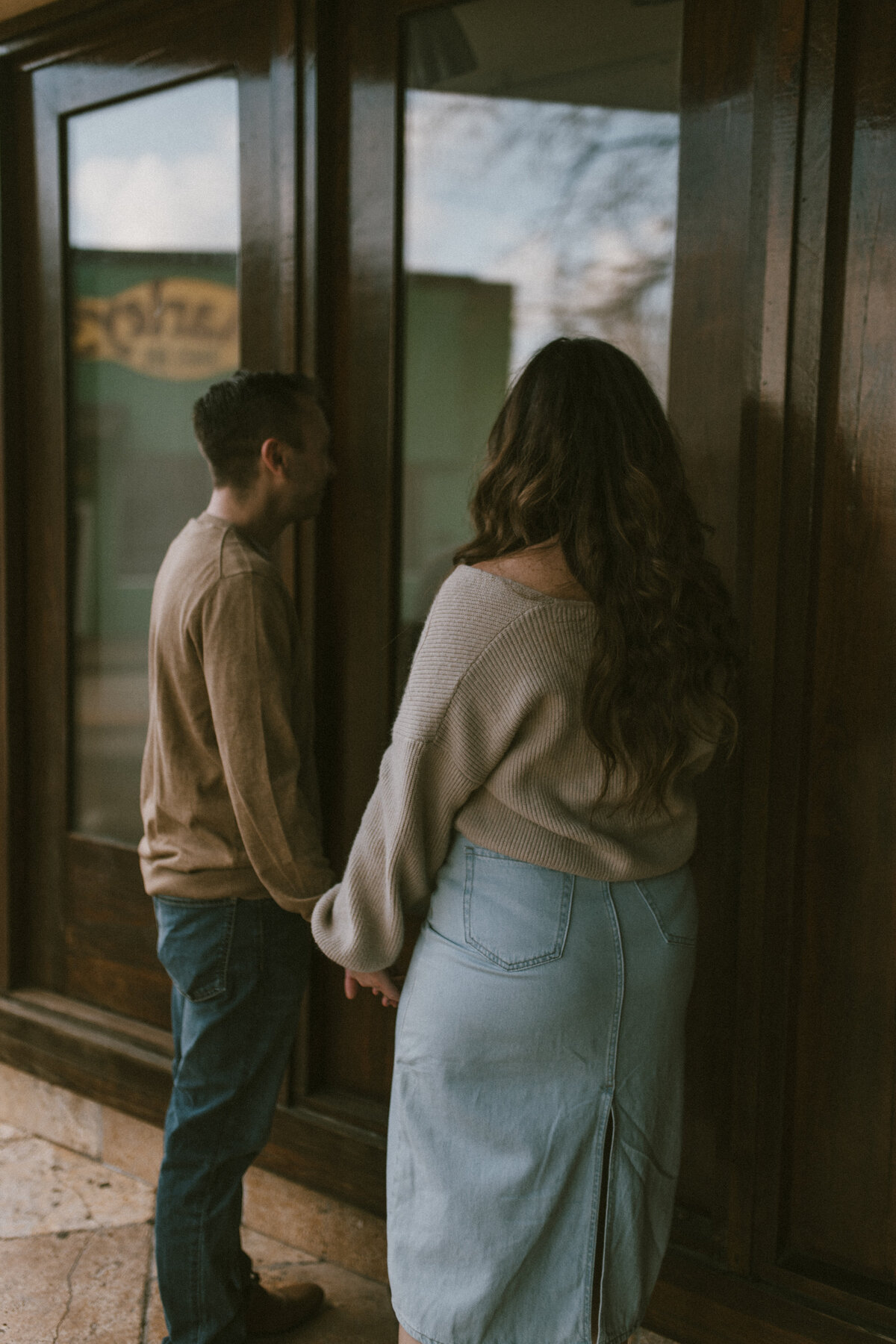 a couple holding hands while window shopping at downtown lafayette stores.