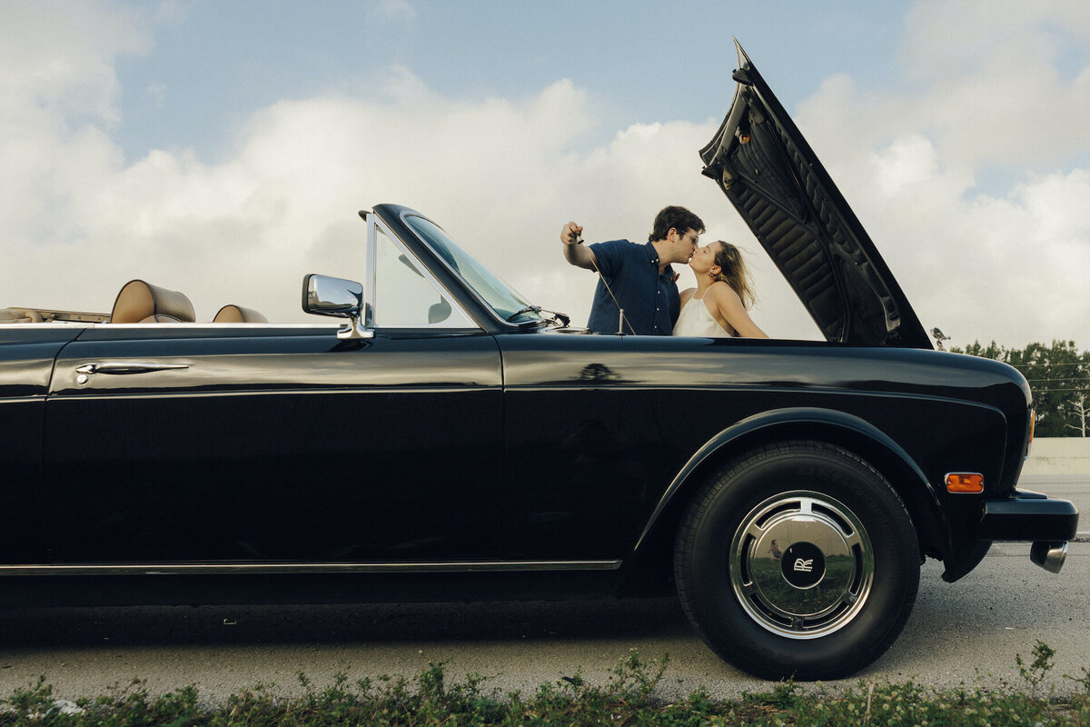 couple poses for portrait next to old classic car