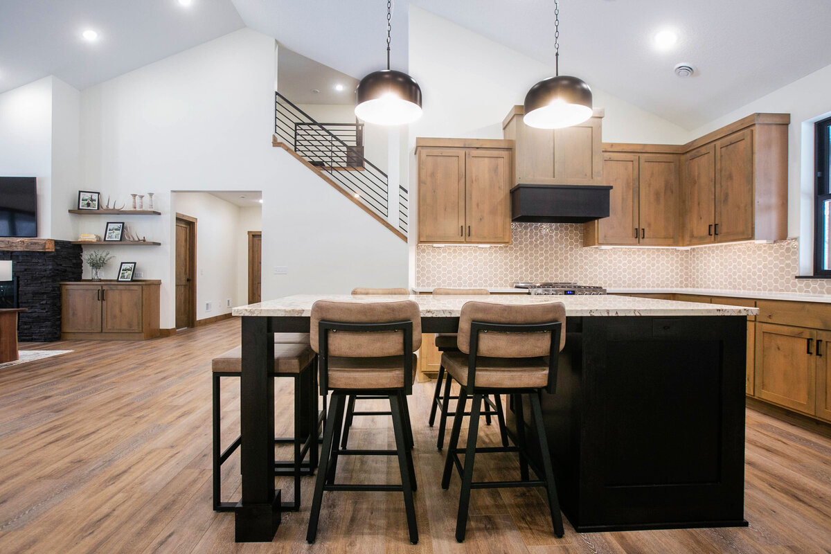 Open kitchen with dark cabinets, large island, and quartz countertops in an Elk River custom home