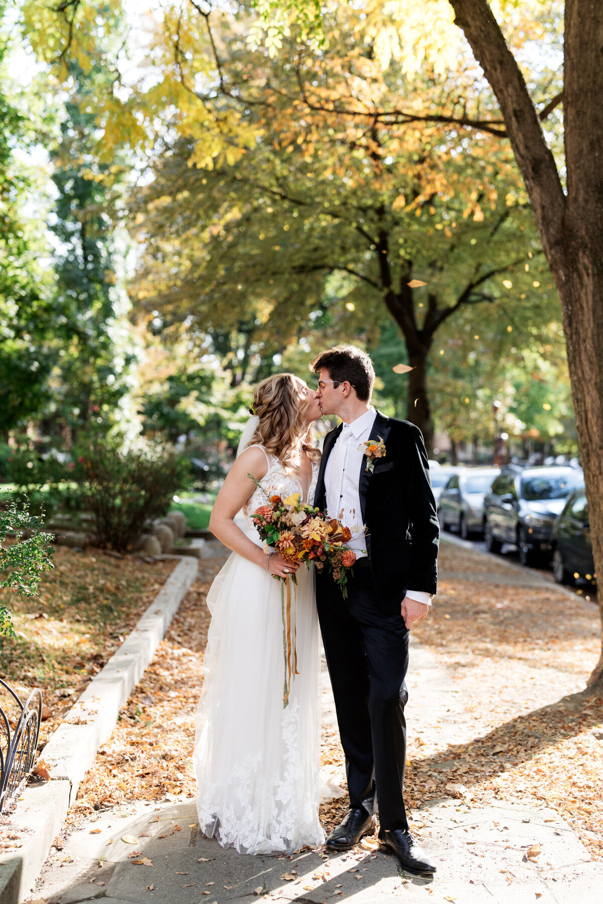 bride and groom kissing under the trees in the fall