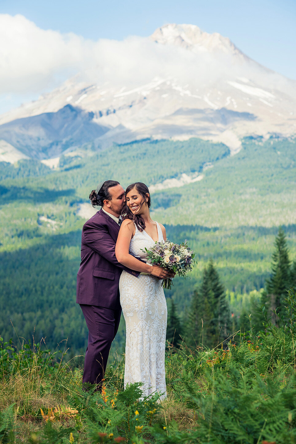 groom hugging bride by mountain