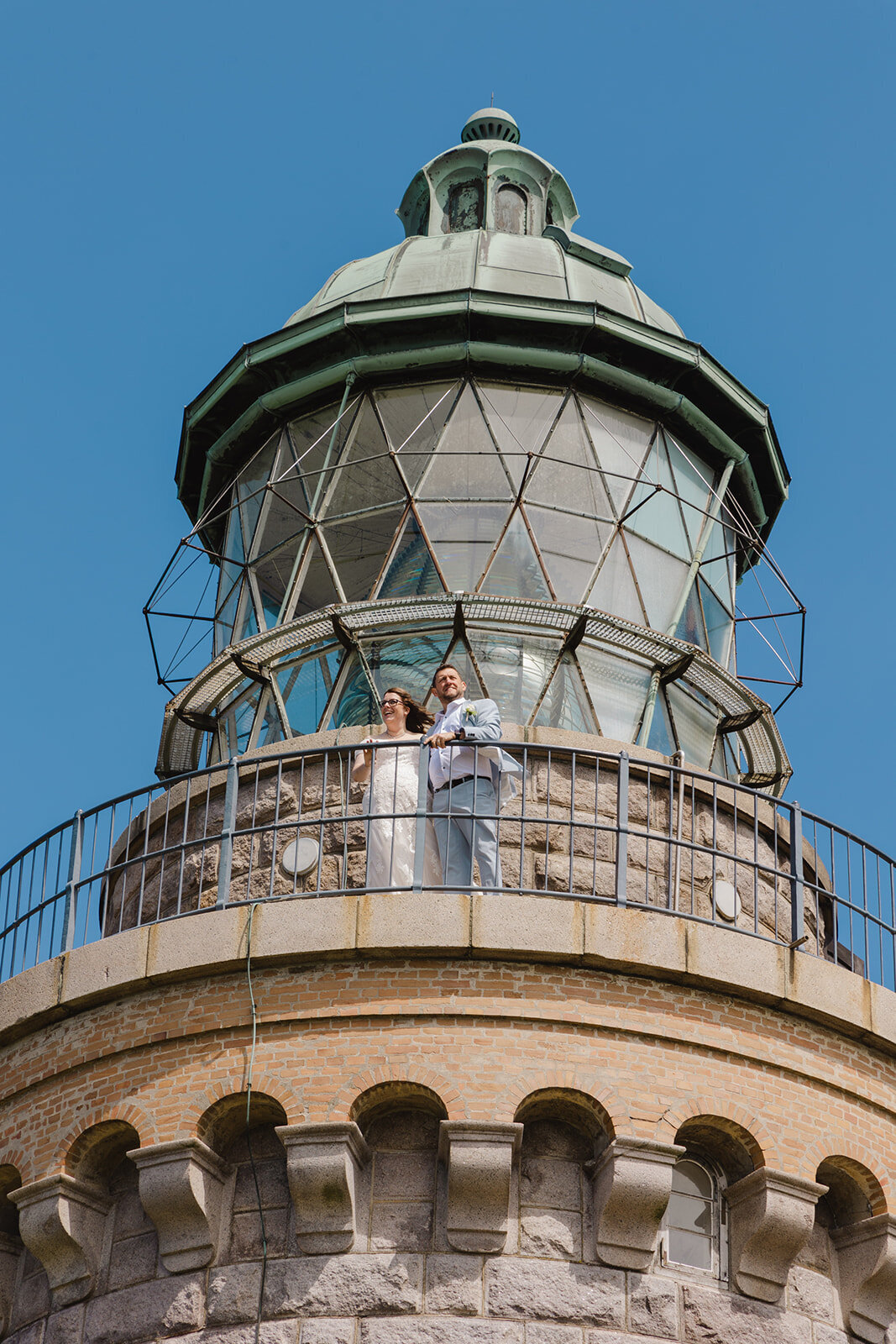 Newlyweds hugging in front of the lighthouse as they explore Bornholm Island during their just the two of us wedding package