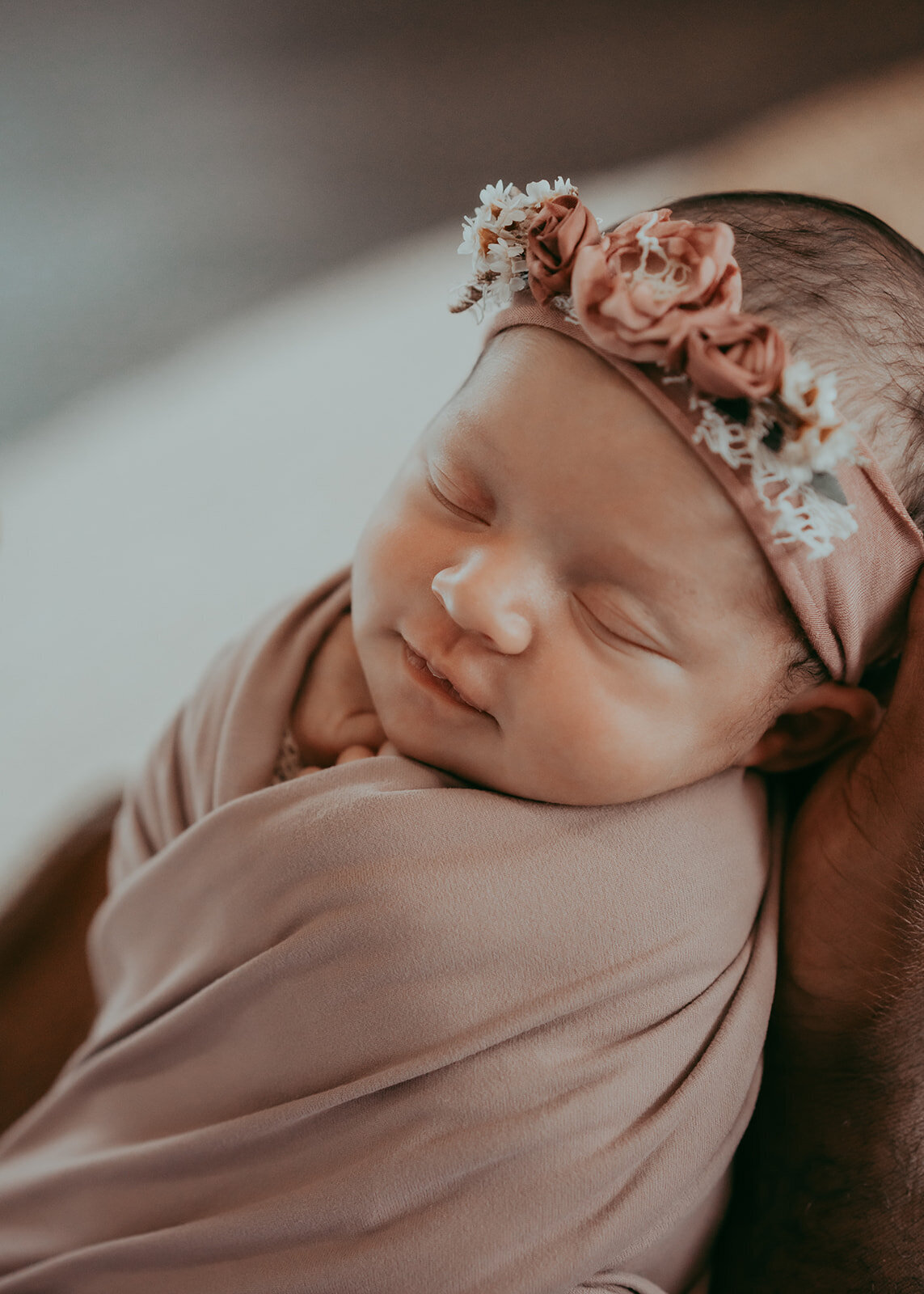 newborn baby girl smiles while sleeping in her dads hands