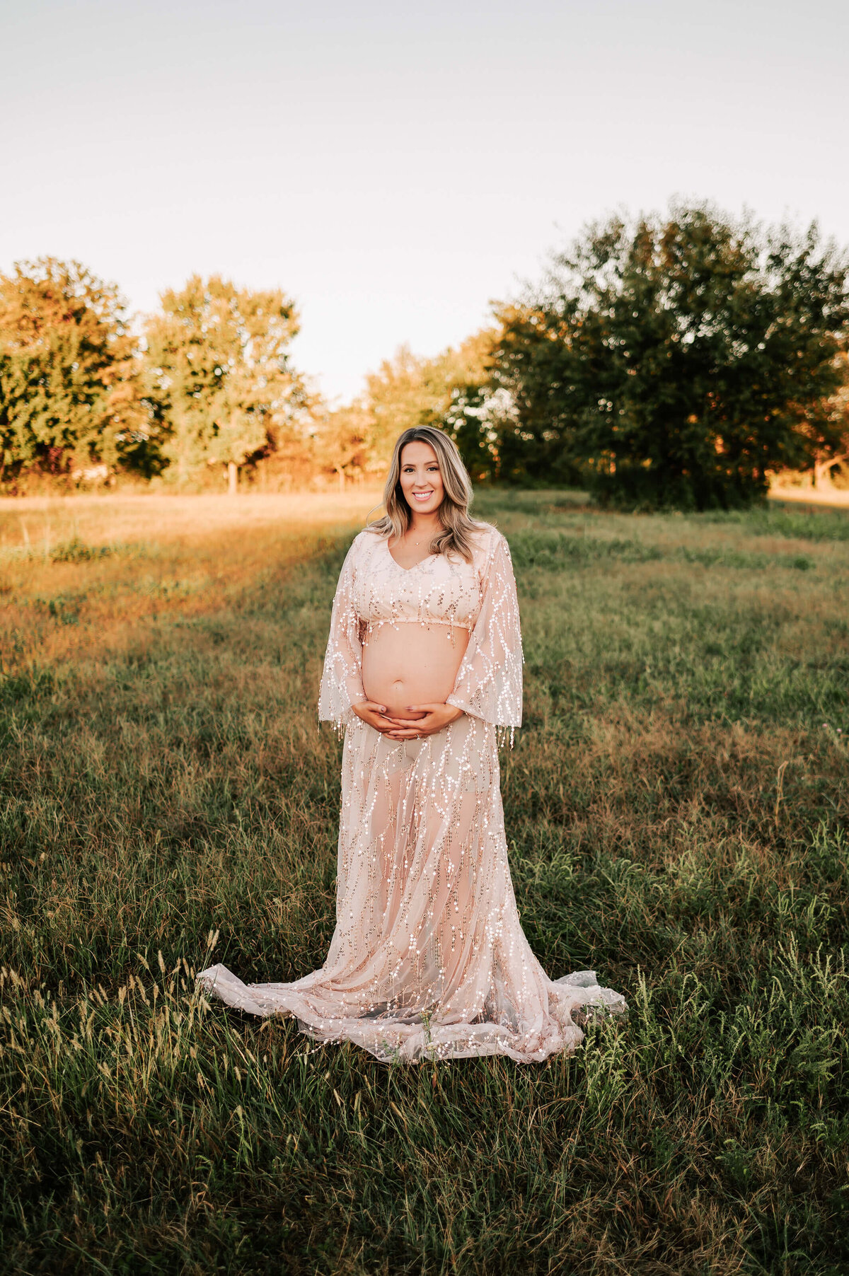 Springfield MO maternity photography of mom in pink dress holding bare belly bump
