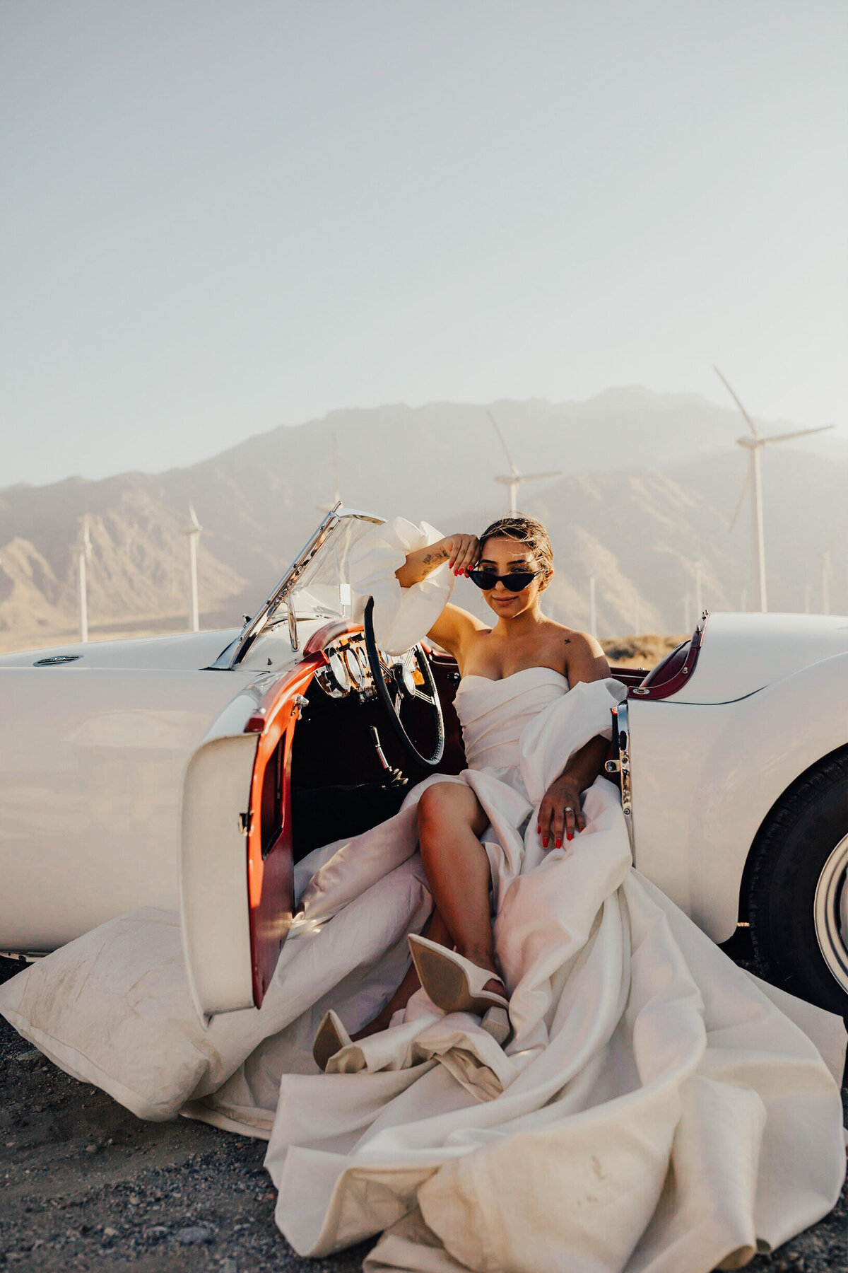 Bride poses in a vintage car after eloping