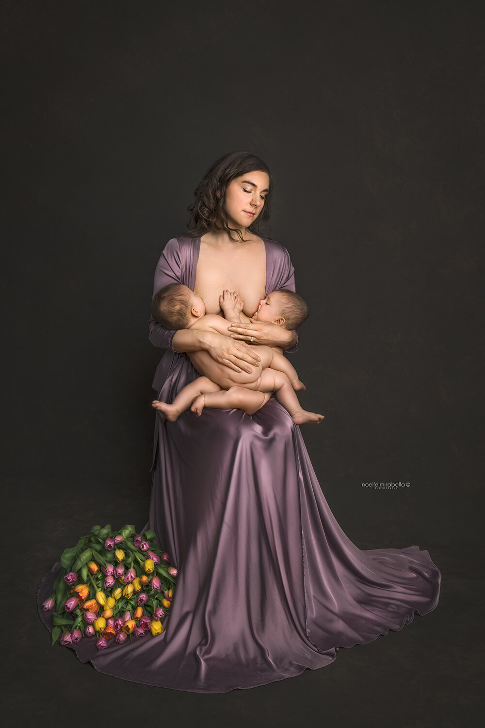 Mother breastfeeding twins at the same time. Soft pastel tones and tulip flowers.