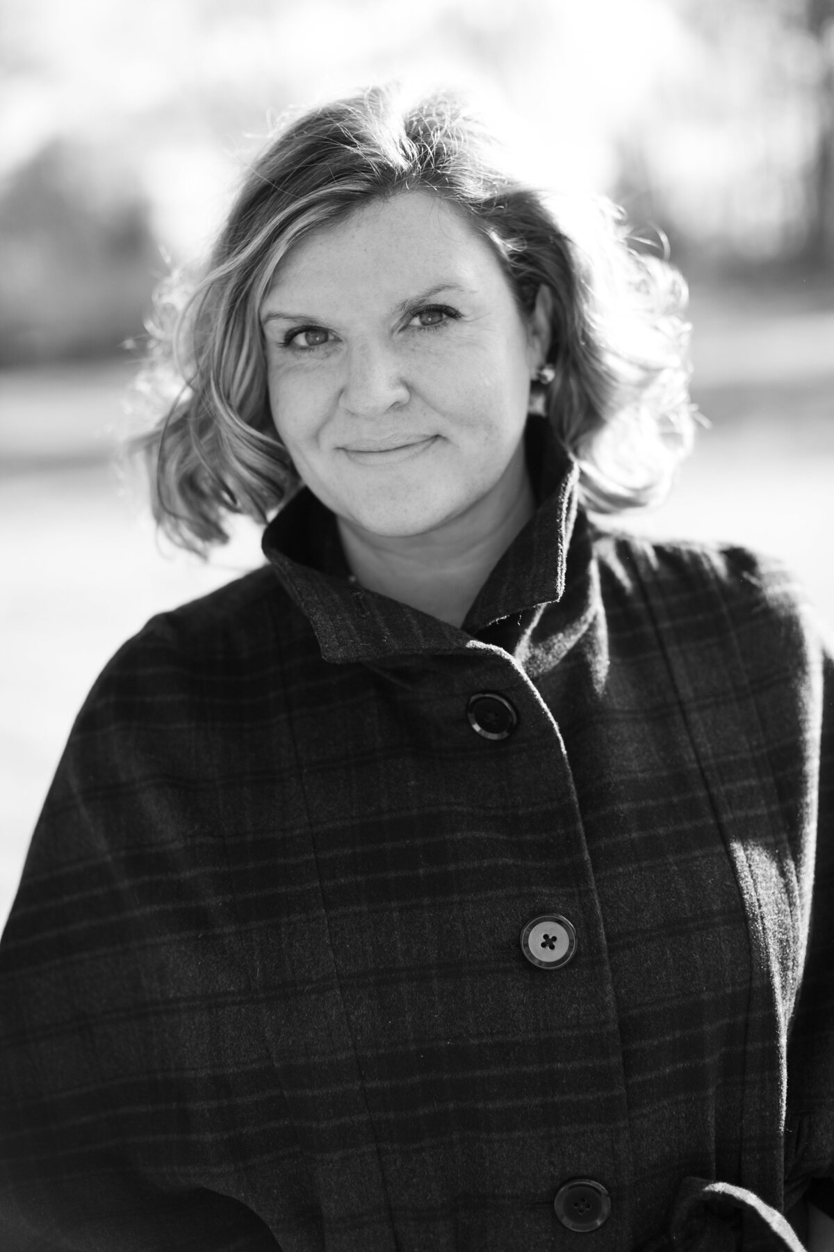 Women wearing plaid jacket looks into camera