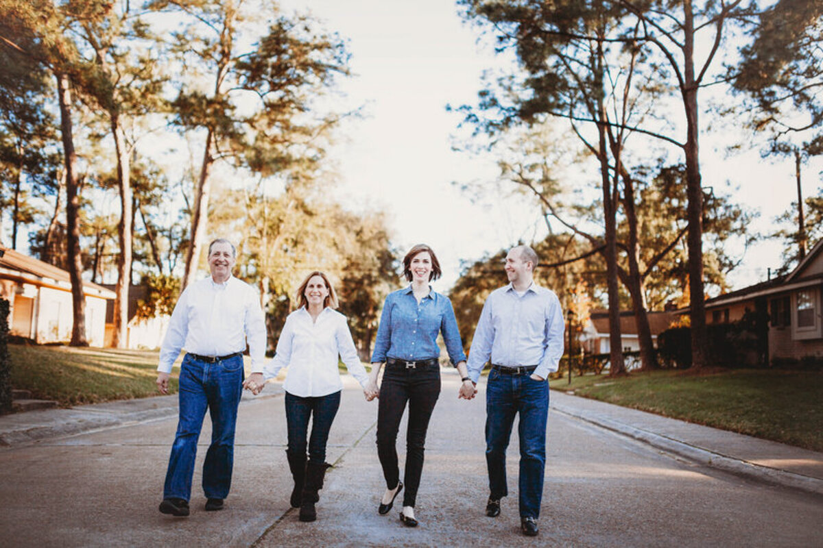 Adult family walking hand-in-hand down a neighborhood street during a natural lifestyle family session in Orlando Florida.