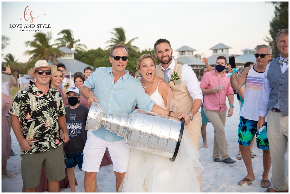 A bride and groom holding the Stanley cup at the Sandbar Restaurant on Anna Maria Island