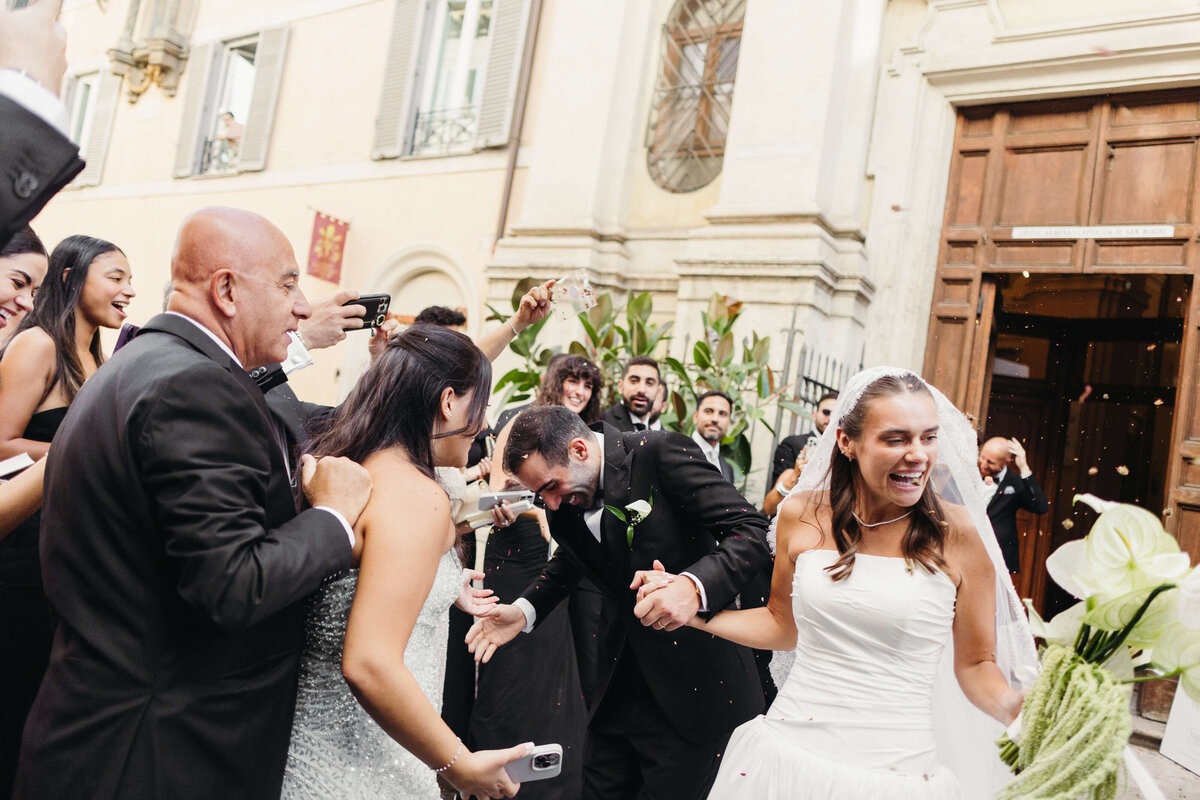 Couple celebrating outside Rome church with friends and family

