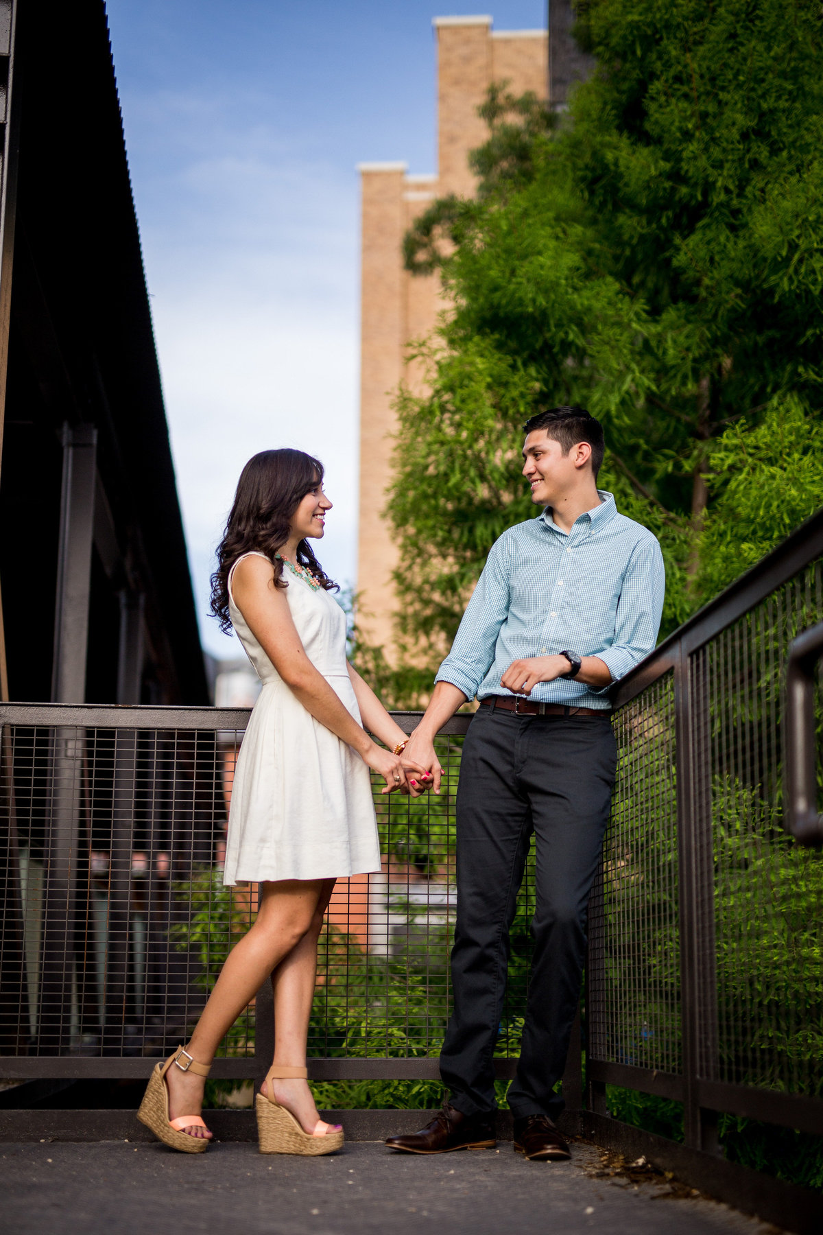 Beautiful young woman engaged to handsome man and they are holding hands at the top of stairs in San Antonio at the Historic Pearl.