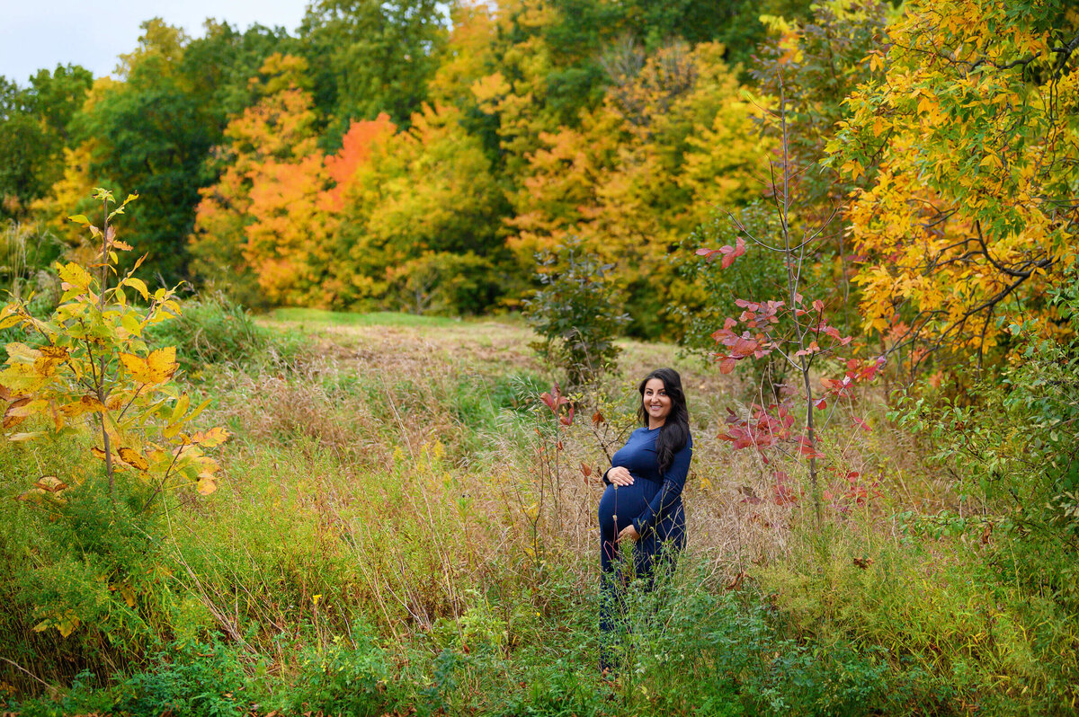pregnant woman wearing a blue maternity dress for her outdoor maternity photography session in Burlington, On
