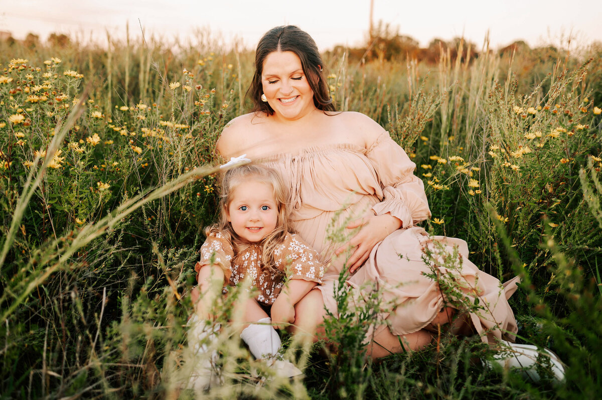 pregnant mom and toddler sitting in flower field during Branson MO maternity photography session