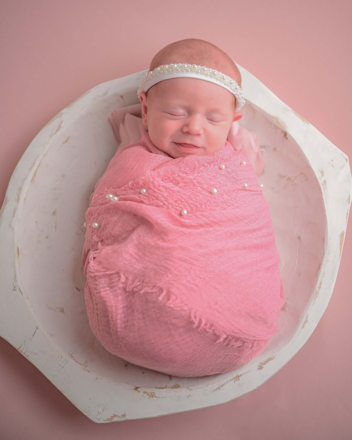 Kitsap  in home newborn session of baby girl sleeping in a white bowl and wrapped in pink.