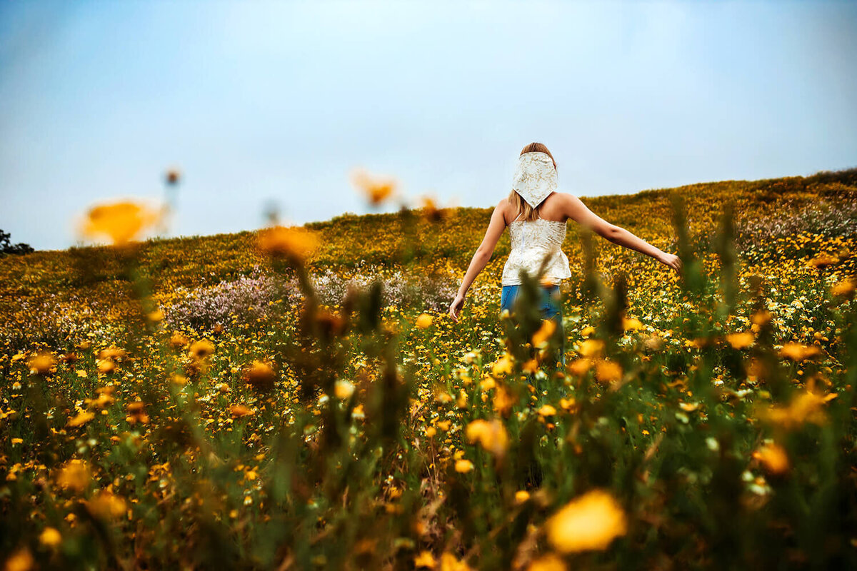 High school senior girl twirling through yellow spring flowers on the hillside of Boulder.