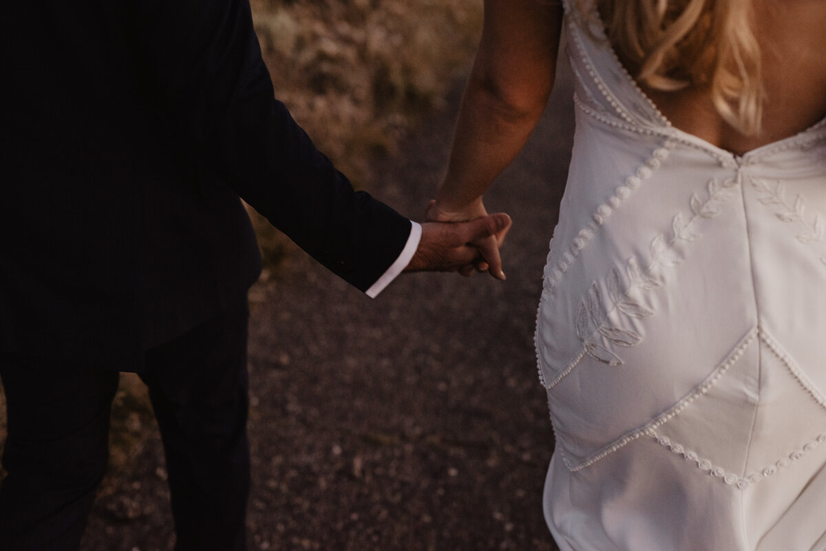 Photographers Jackson Hole capture couple holding hands in wedding attire