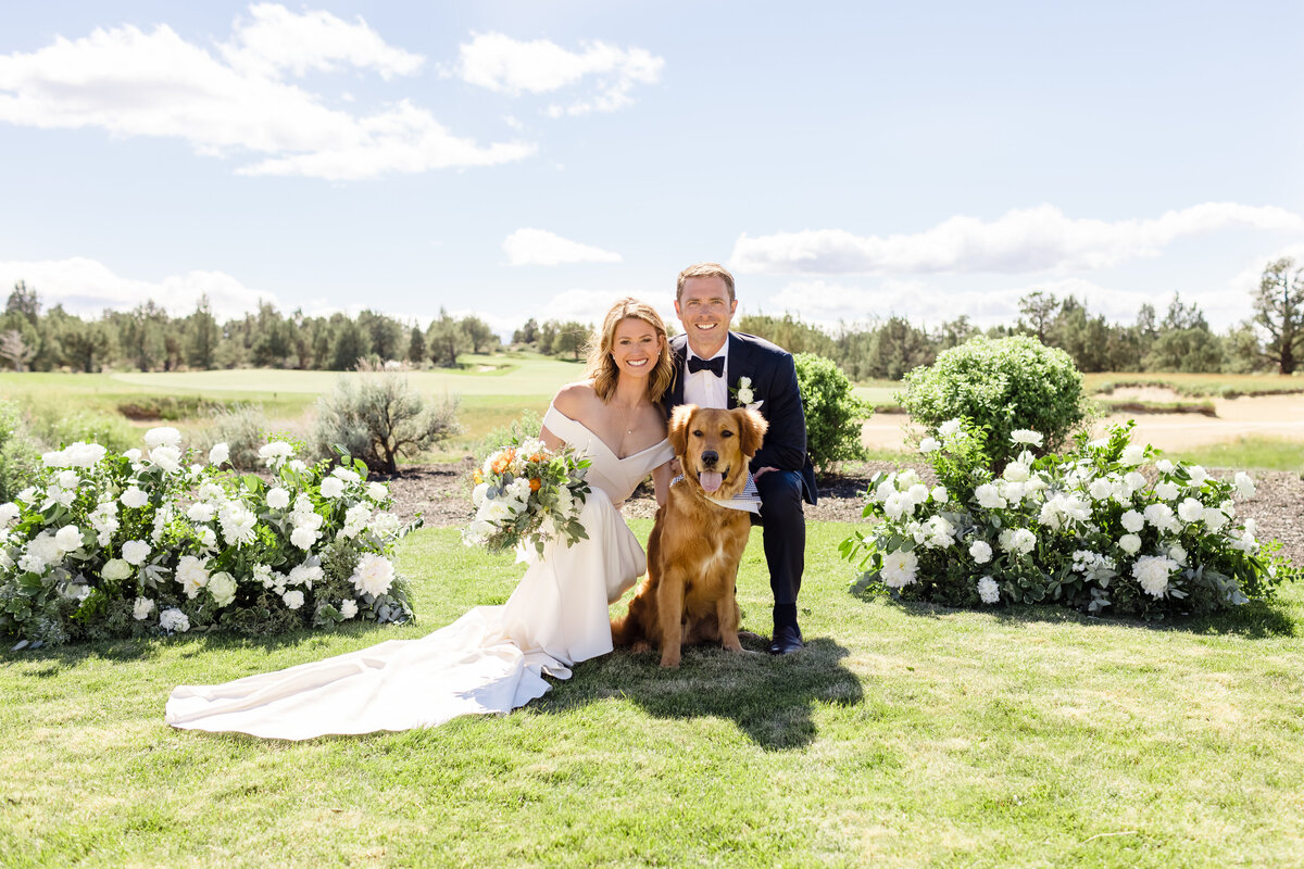 Bride and groom with their dog between white floral hedges on event island at Juniper Preserve
