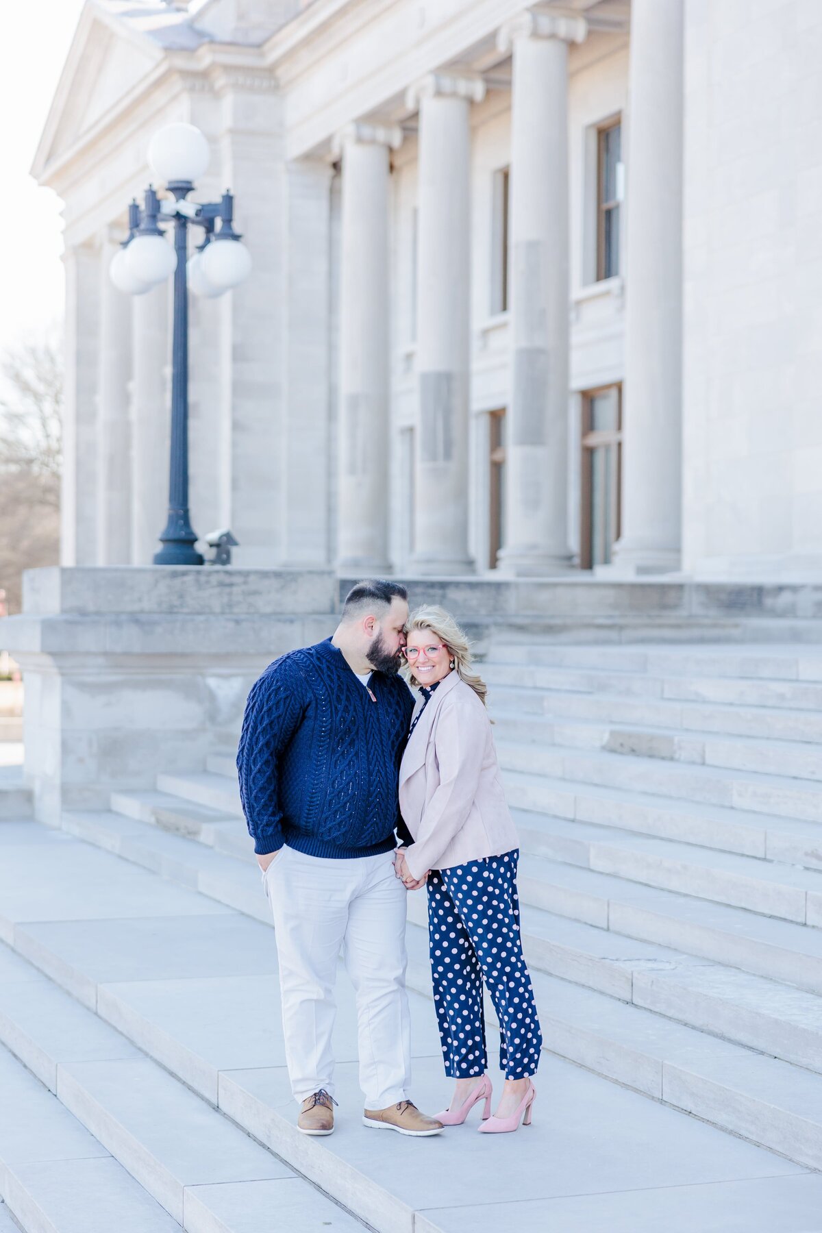 A couple in blue and pink stand outside the Arkansas capitol steps in the wind.