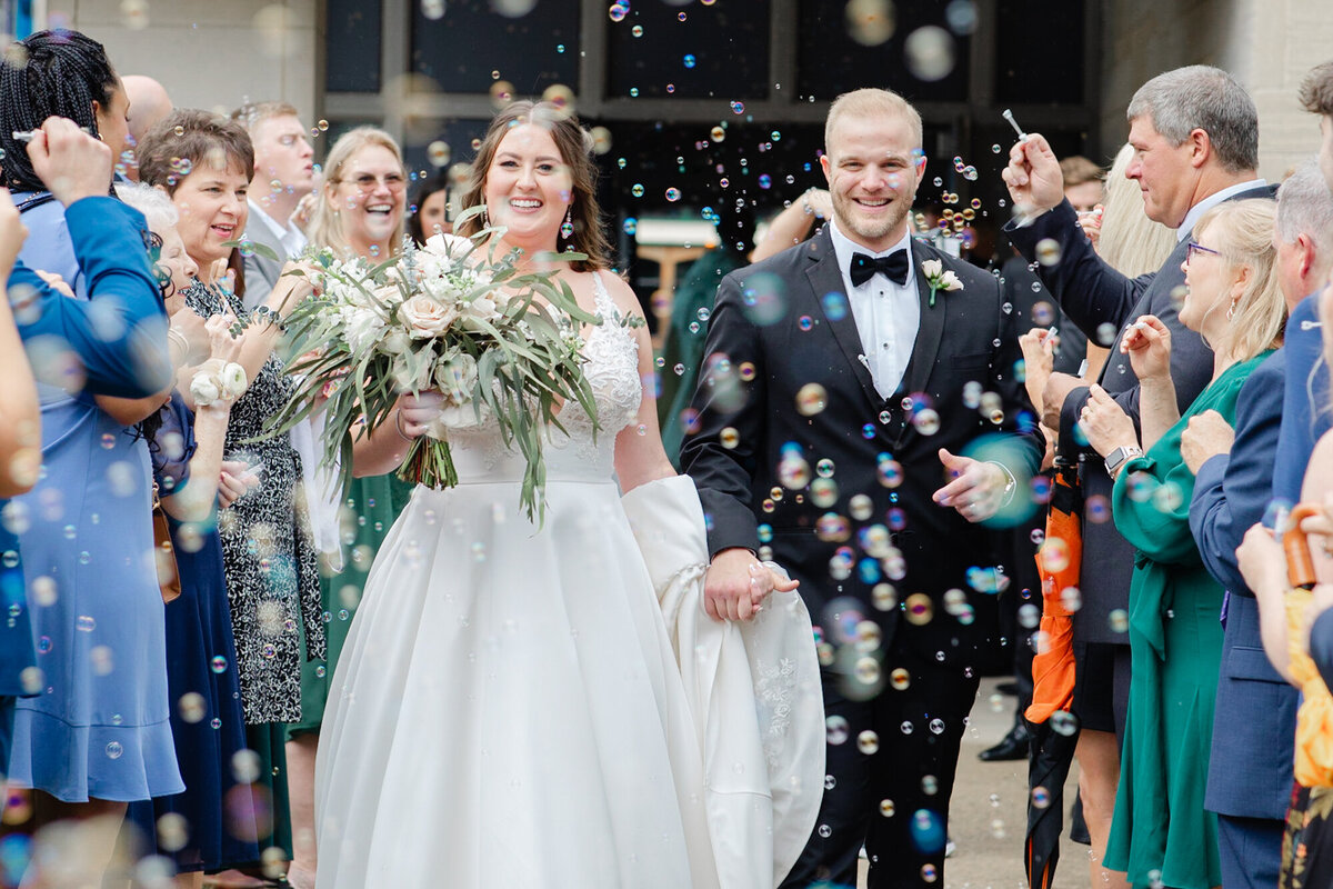 bride and groom exit Church while guests blow bubbles in Grandview Ohio