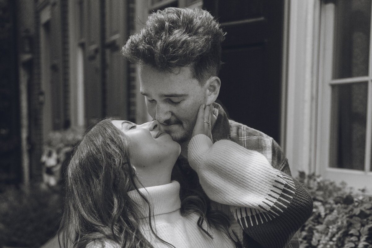 Black and white portrait of couple kissing in Old City street.