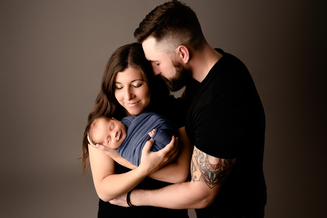 Brighton Newborn Photographer mom and dad holding baby by For The Love Of Photography