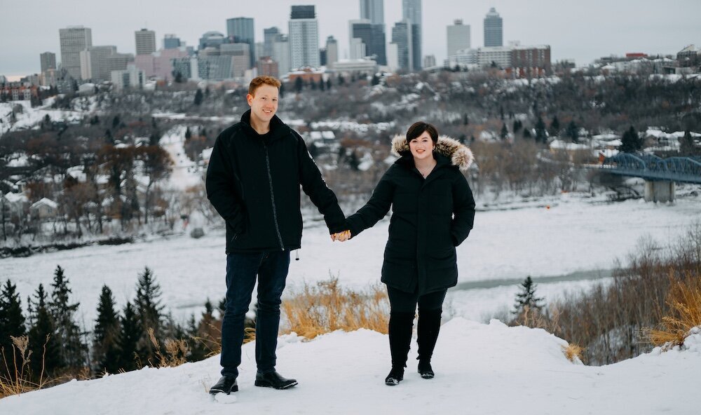 Edmonton couple hold hands in their black winter coats with snow on the ground