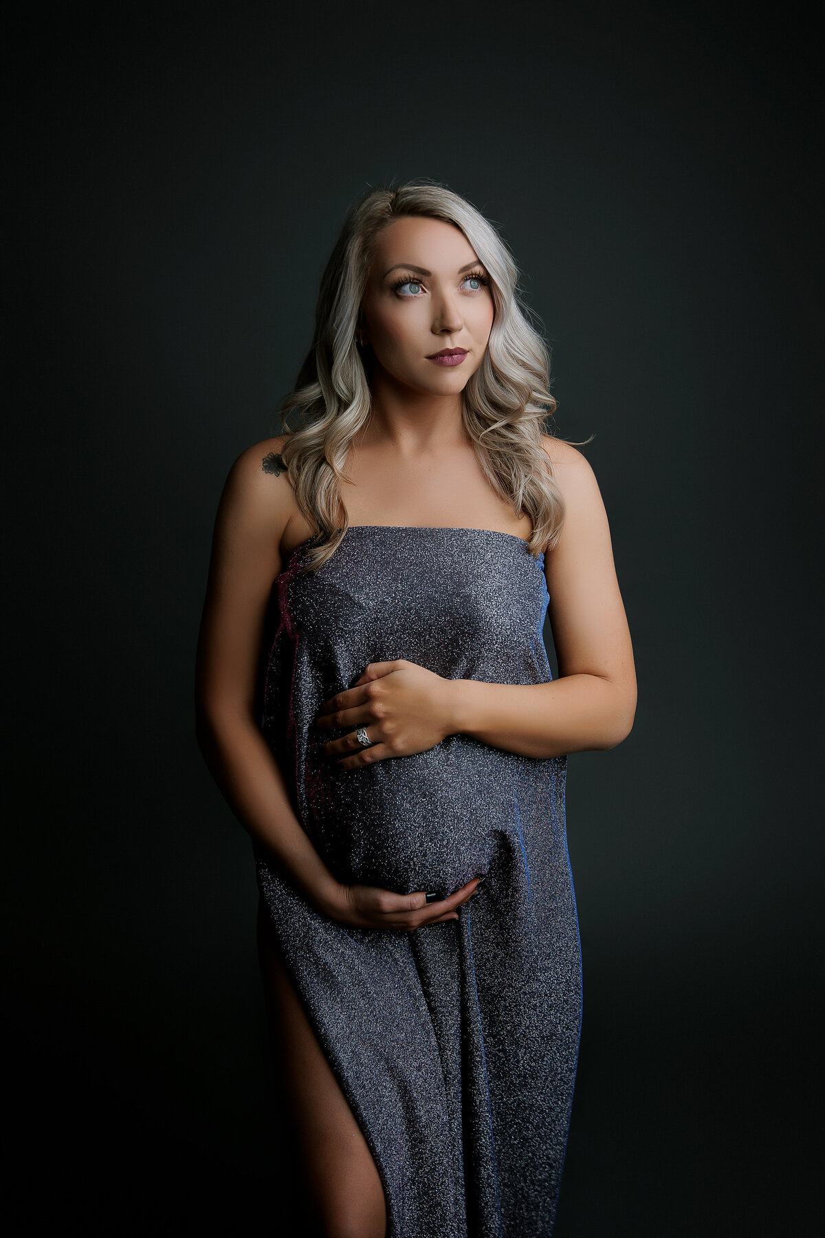 pregnant mother holding her belly beump wearing sparkly dark blue dress