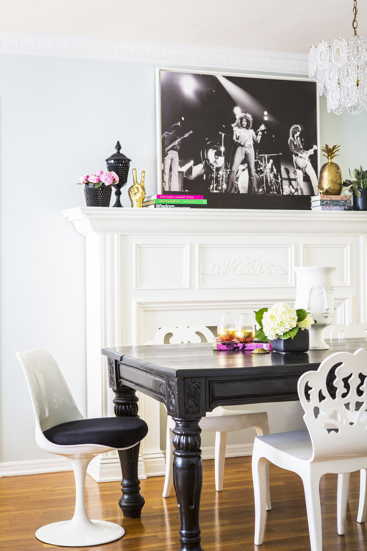 Rustic modern dining room with black dining table, white chairs, and black and black and white Led Zeppelin art