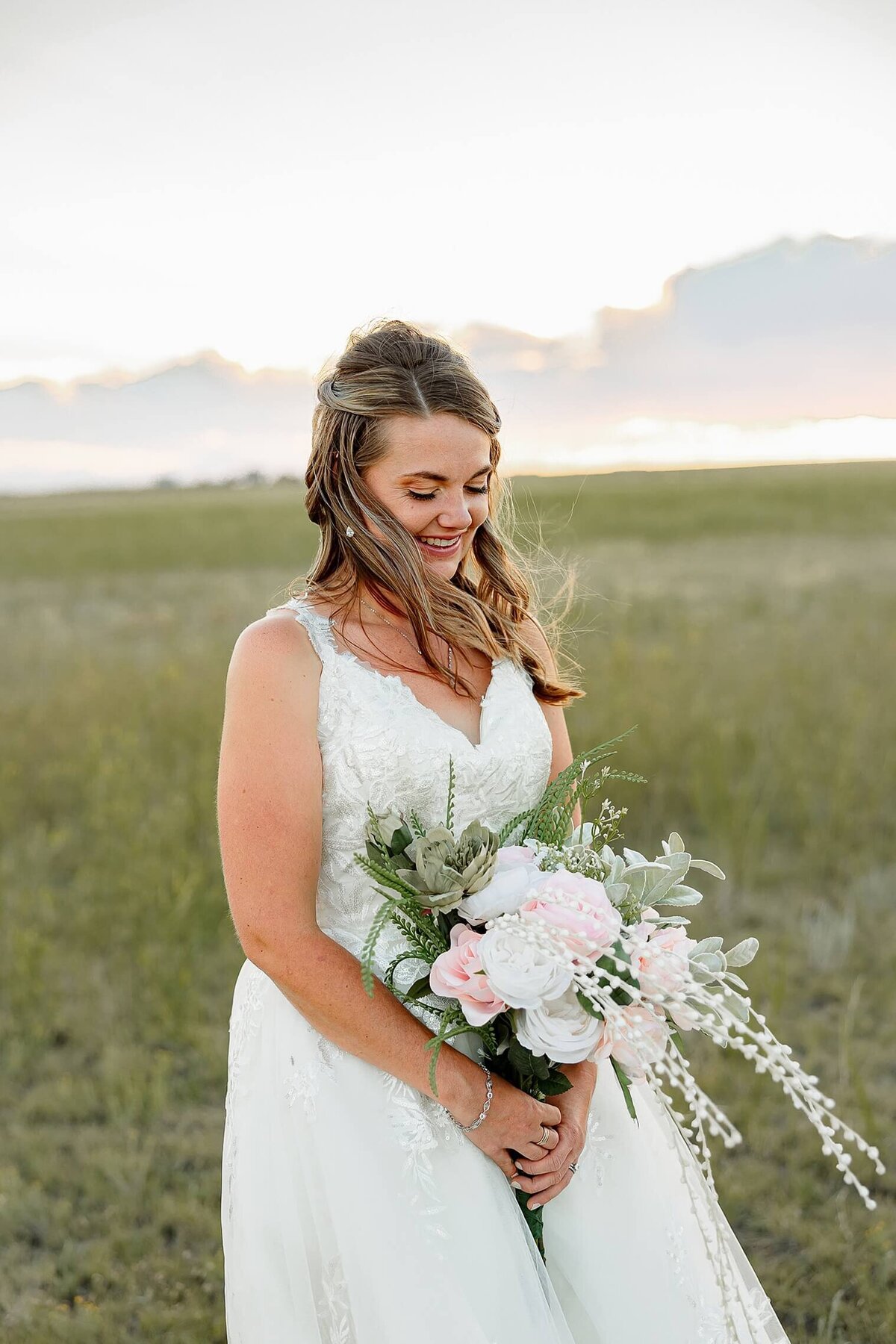 wedding photos of Bride portrait of brown haired bride looking down at bouquet and smiliing.