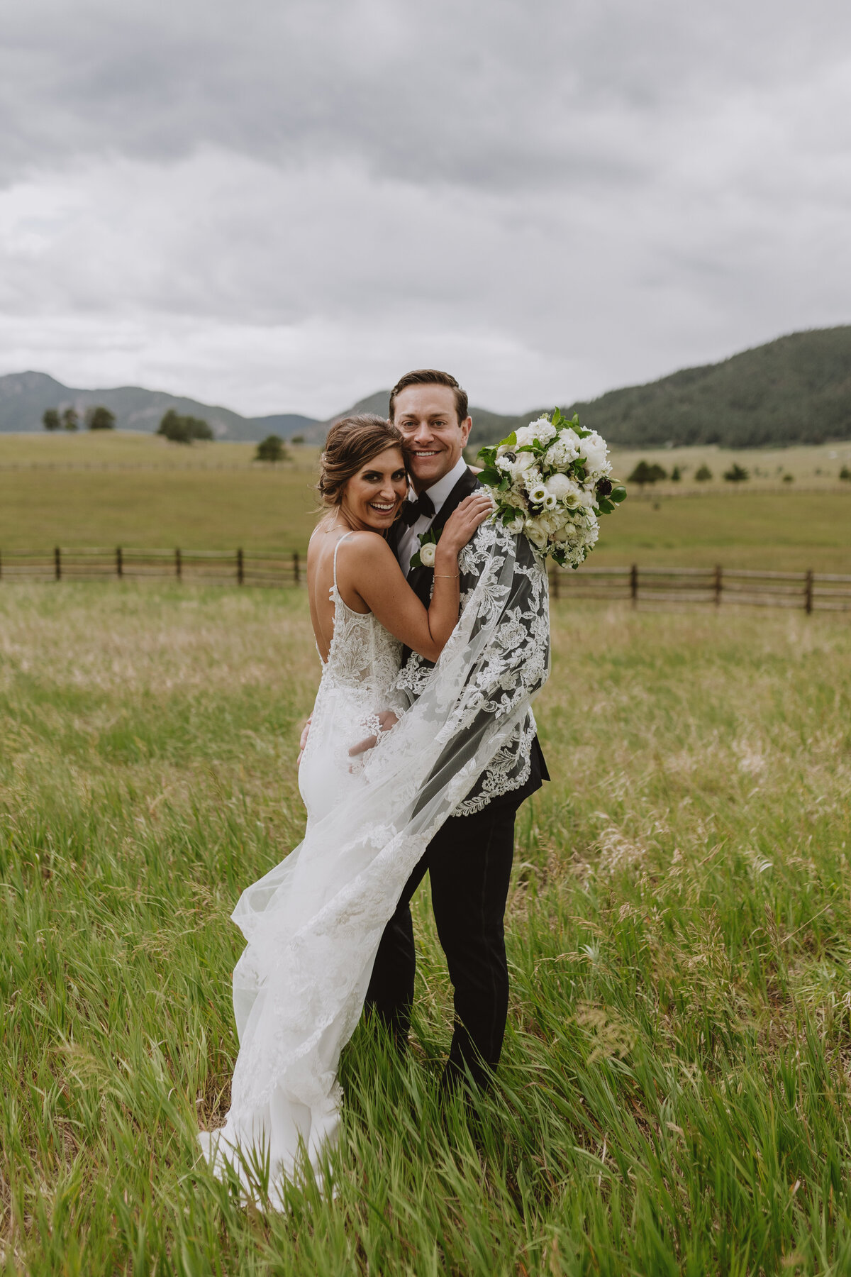 bride and groom smiling in a field