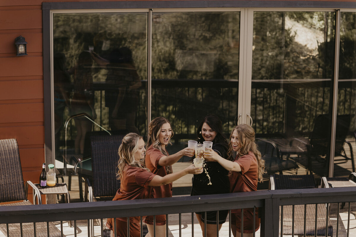 Bride and bridesmaids doing cheers with glasses