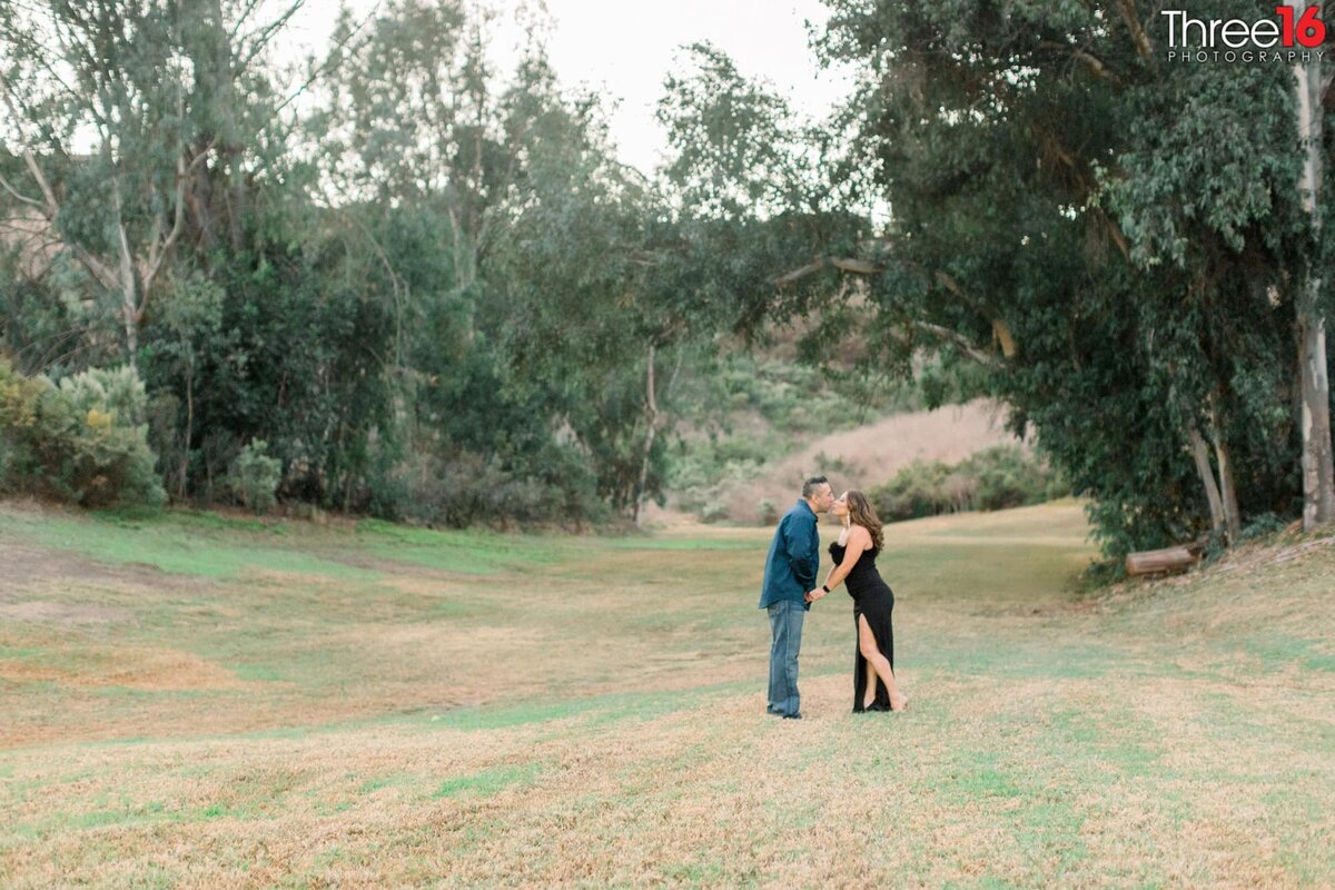 Engaged couple stop for a kiss along the green trail at Laguna Niguel Regional Park