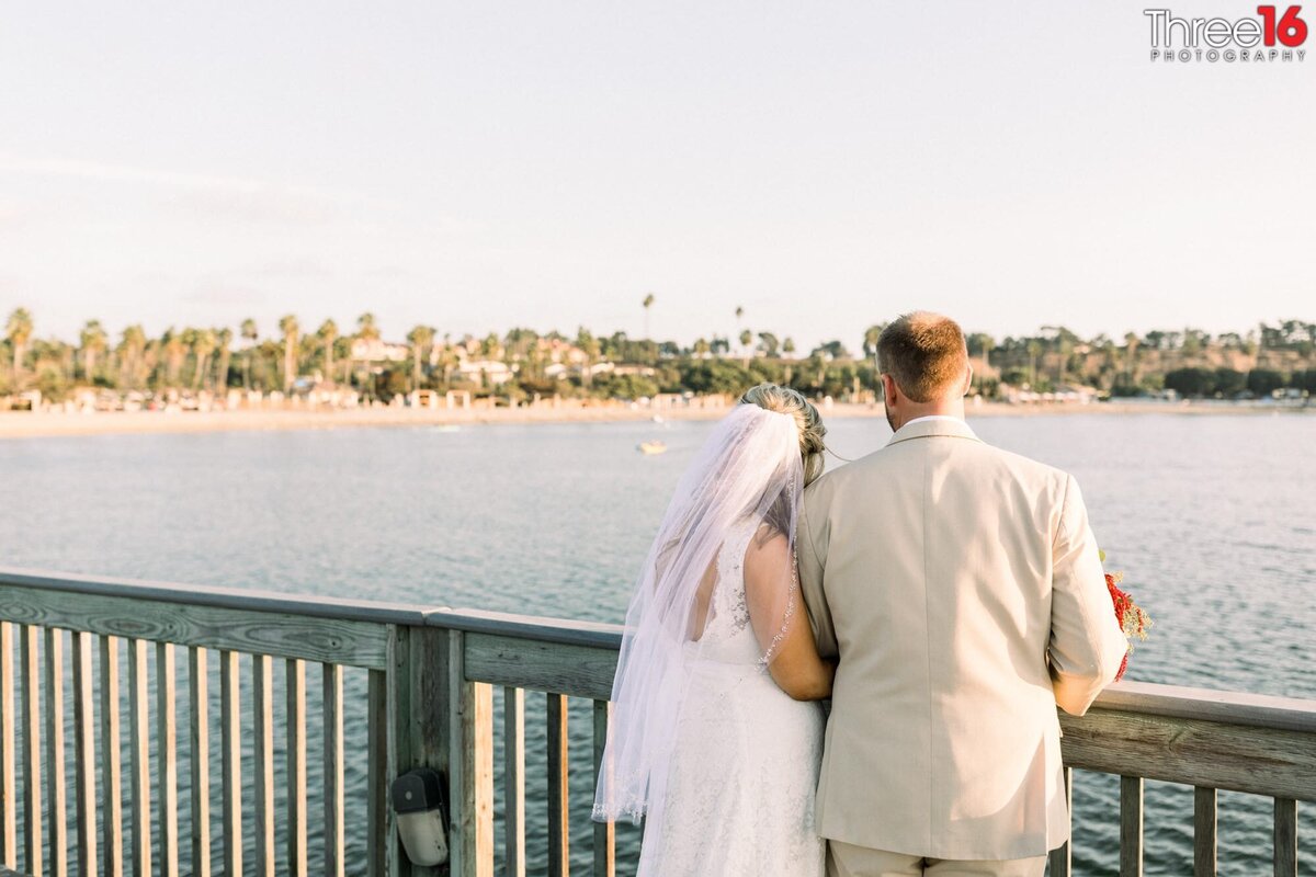 Bride and Groom look out over the ocean together from a bridge