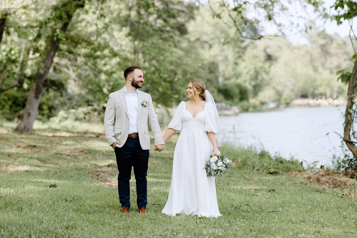 bride and groom standing by lake after outdoor spring wedding ceremony