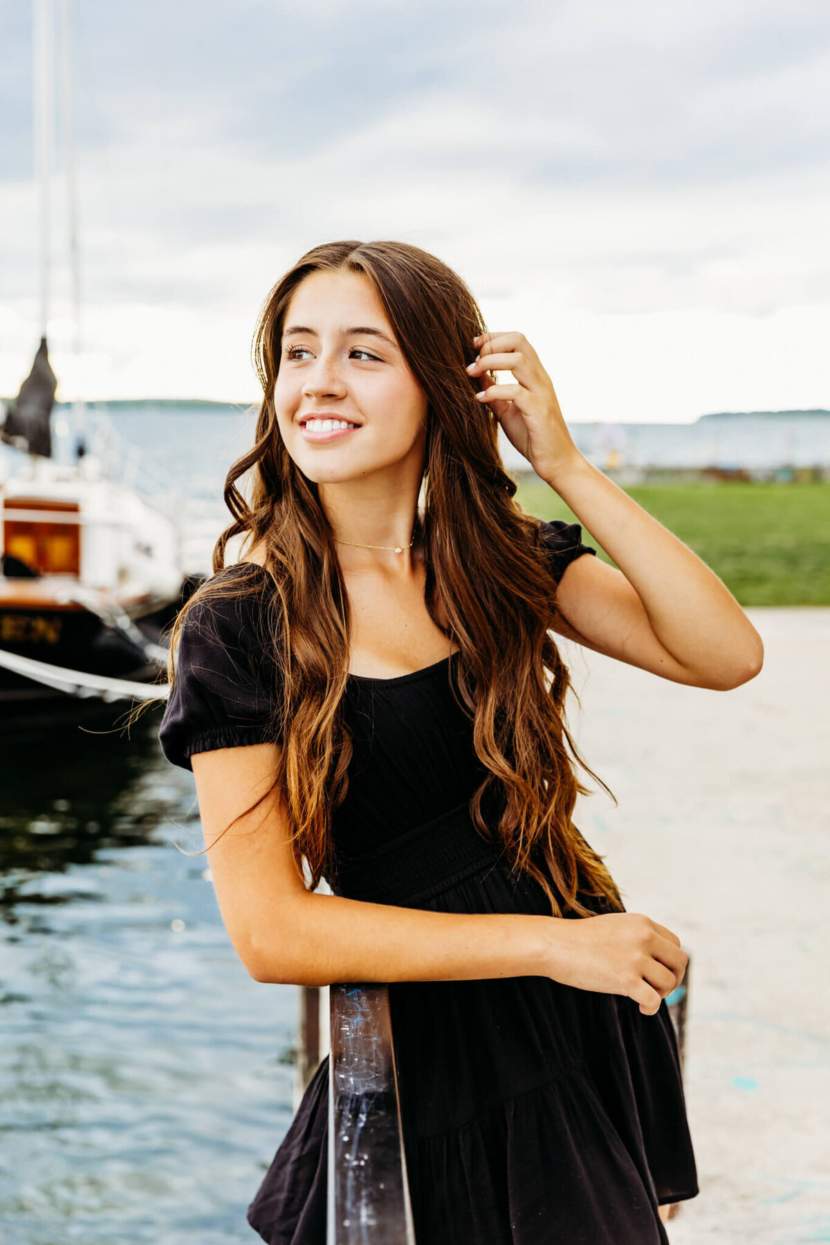 photo of a beautiful teenage girl smiling as she looks over the lake for her senior photography session