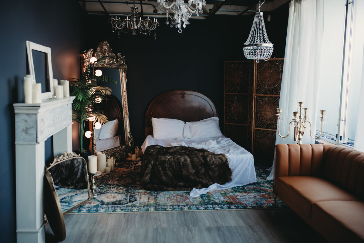 Moody luxury boudoir bedroom set at a Chicago photography studio with dramatic shadows and sensual lighting highlighting feminine curves on a plush bed.