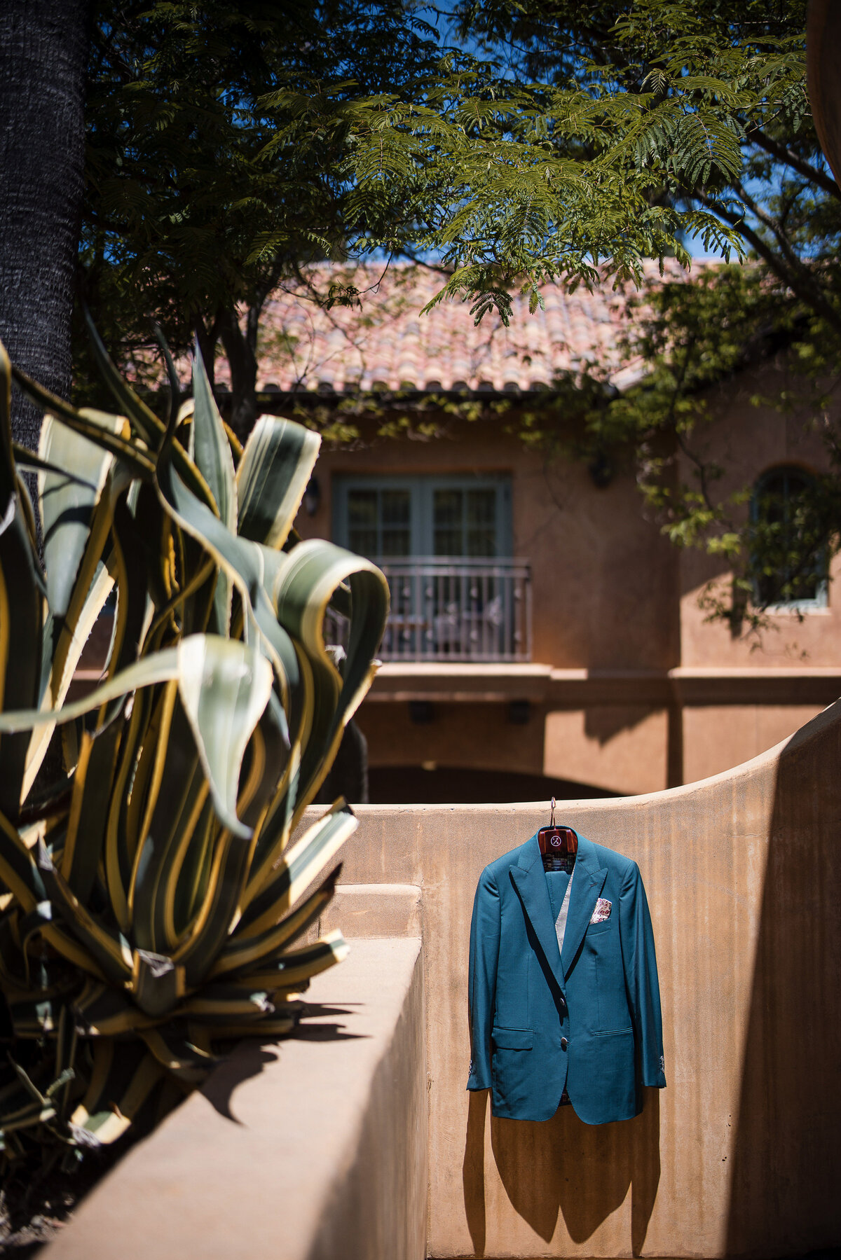 A groom's custom suit hangs outdoors at a destination wedding at Nestldown in Los Gatos, California