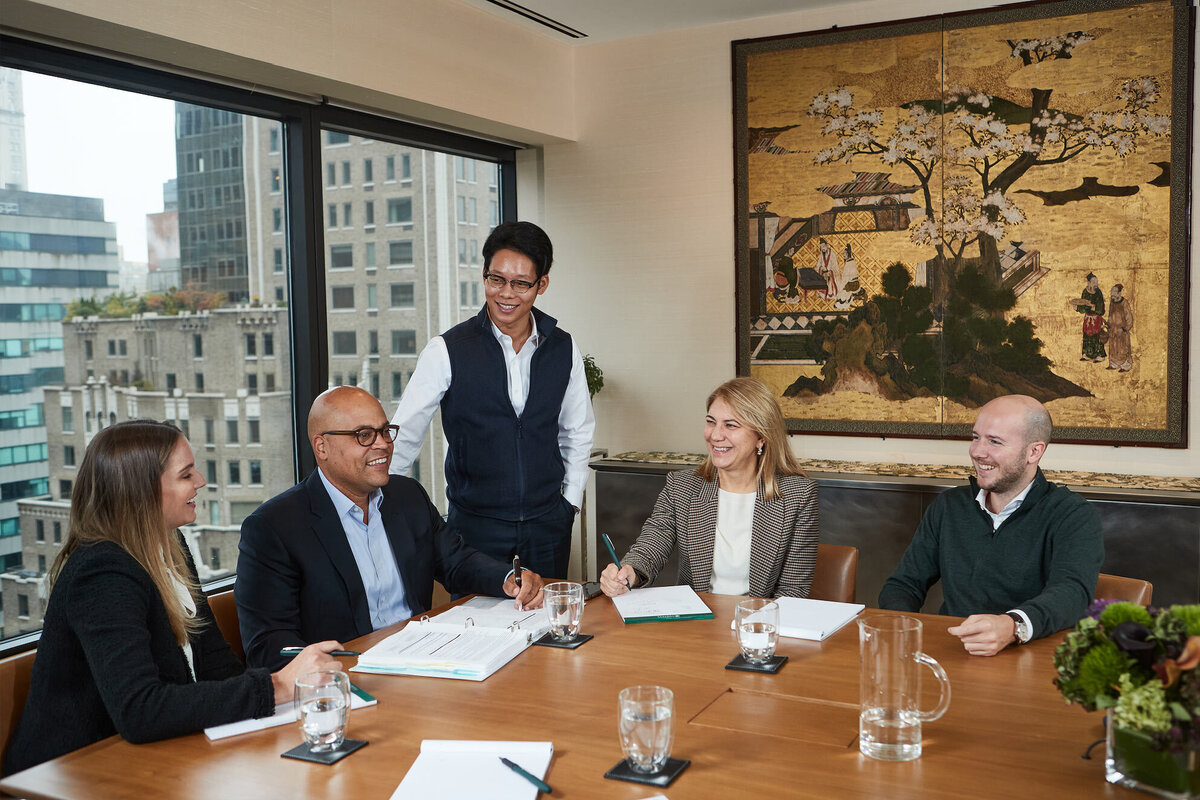 Corporate team discussion in the conference room at Cornell Capital Offices, featuring engaged professionals around a boardroom table, captured by Ylva Erevall.