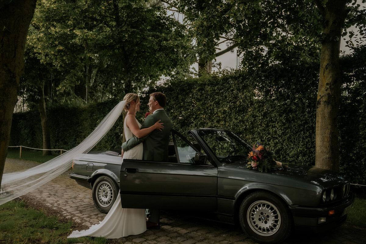 Pasgetrouwd koppel poseert tijdens trouwreportage voor groene vintage auto