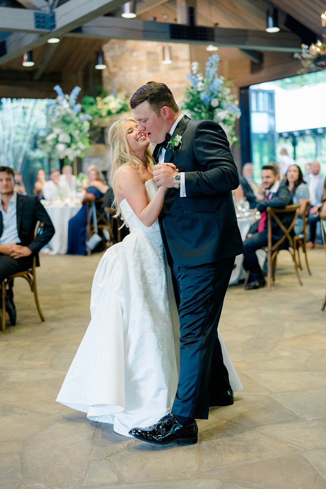  Bride and groom sharing their first dance surrounded by floral installations and guests at Old Edwards Inn wedding reception.