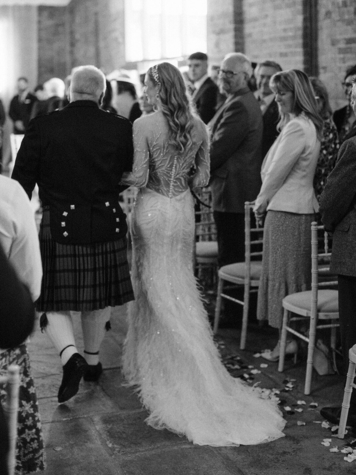 father and daughter walking down the aisle captured from behind