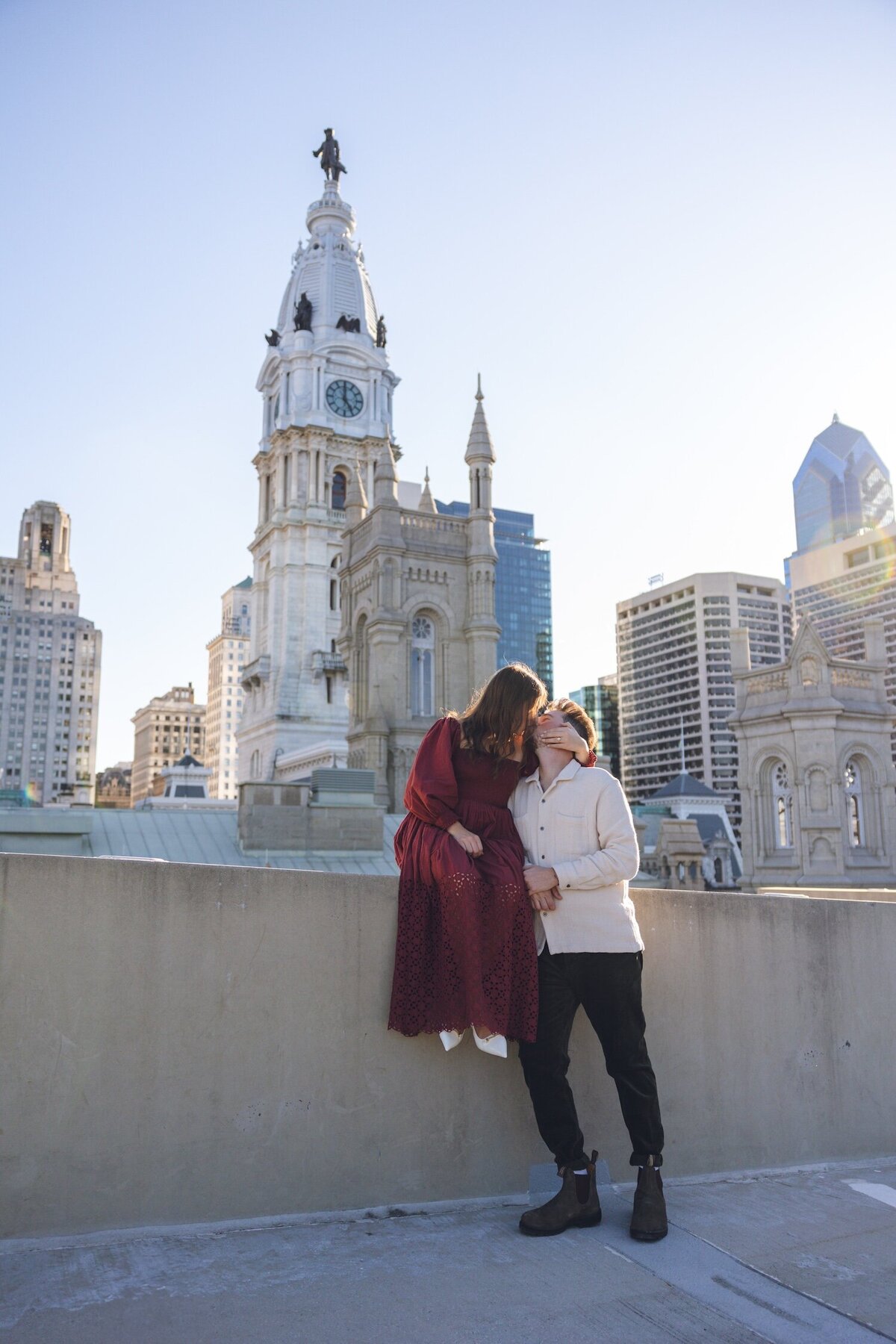 Couple holding hands and laughing near historic City Hall architecture.