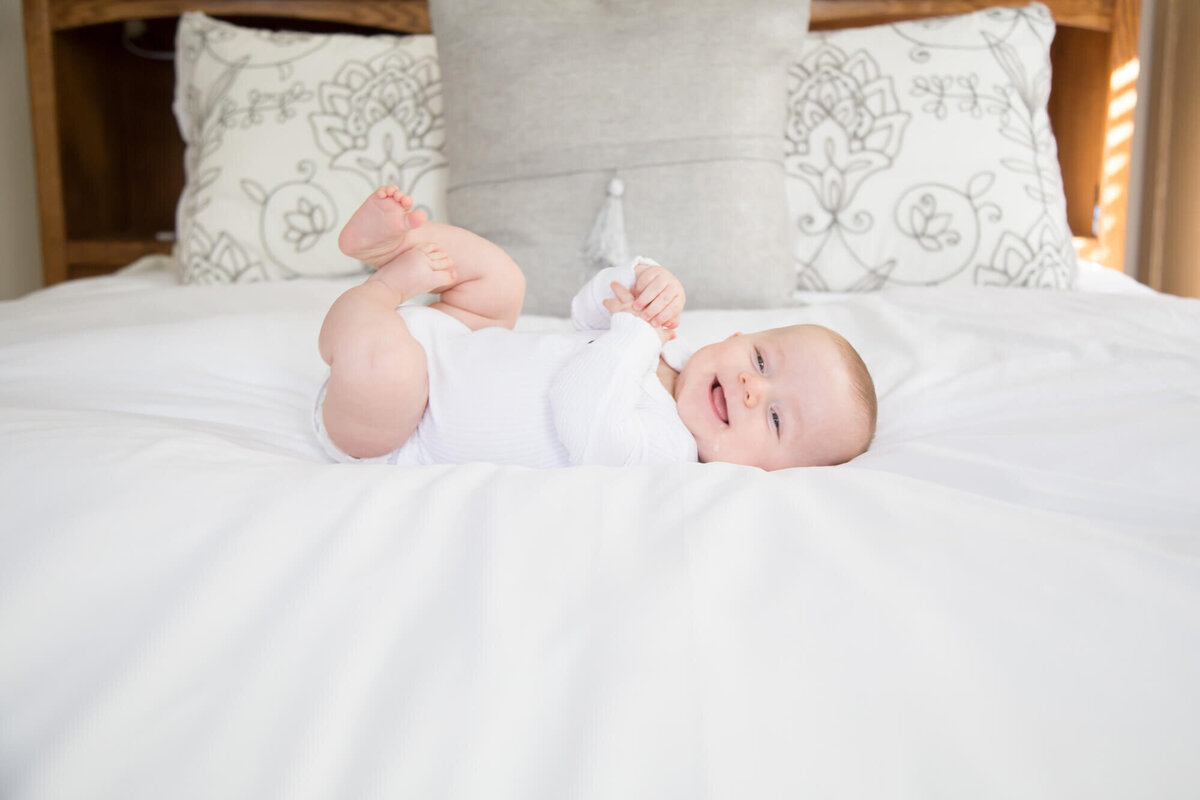 Infant baby boy smiling while laying on a bed